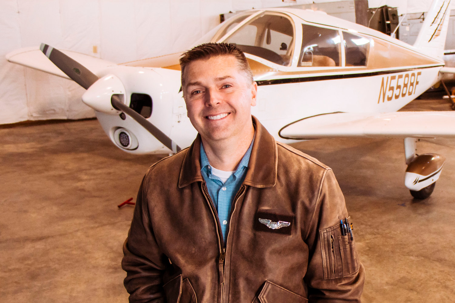 Airport Operations Coordinator Brandon Rakes smiles and poses for a photo in front of his aircraft in a hangar at the Chehalis-Centralia Airport on Wednesday.