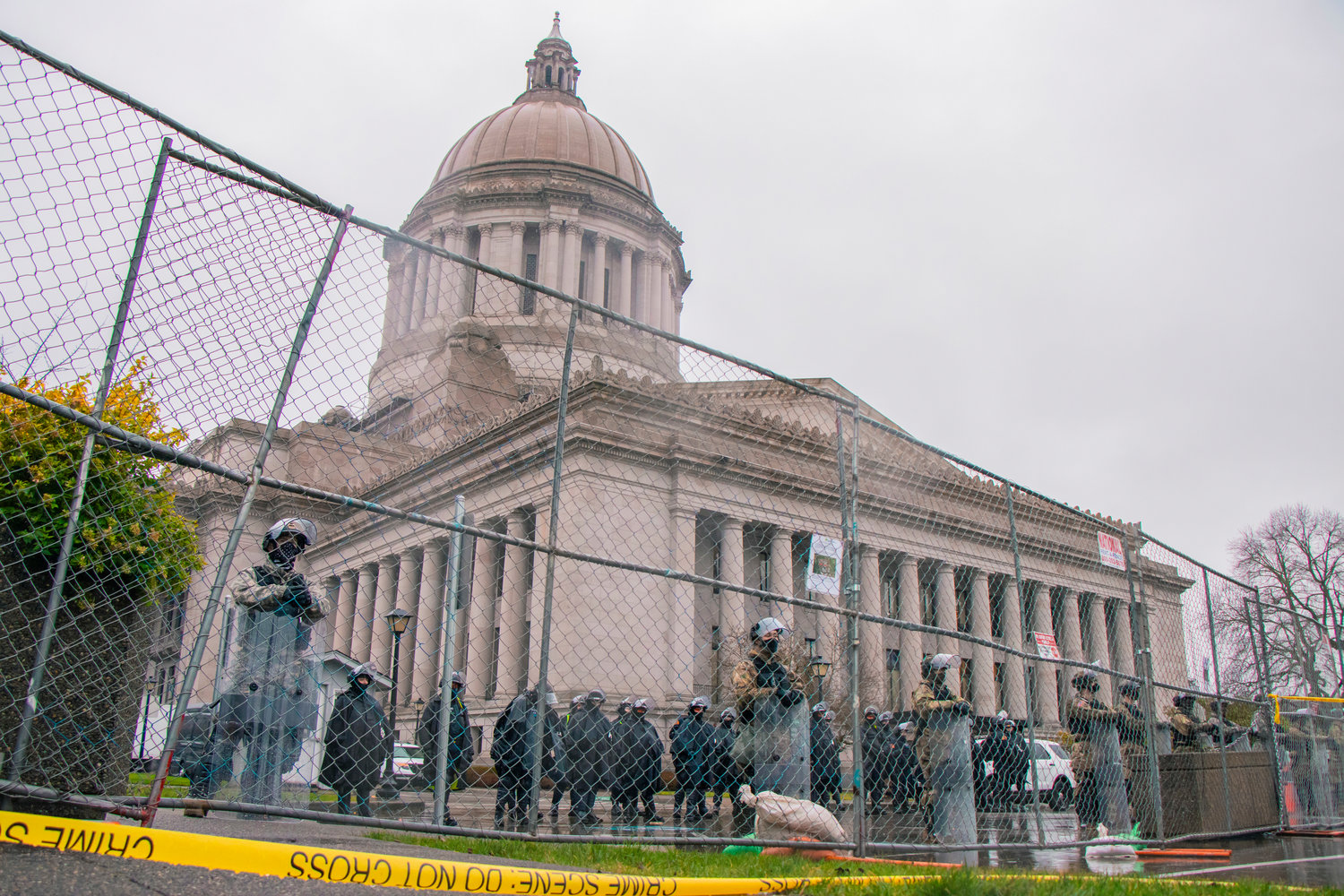 U.S. Army National Guardsmen and members of the Washington State Patrol line a fence outside of the Washington State Capitol building last month in Olympia.