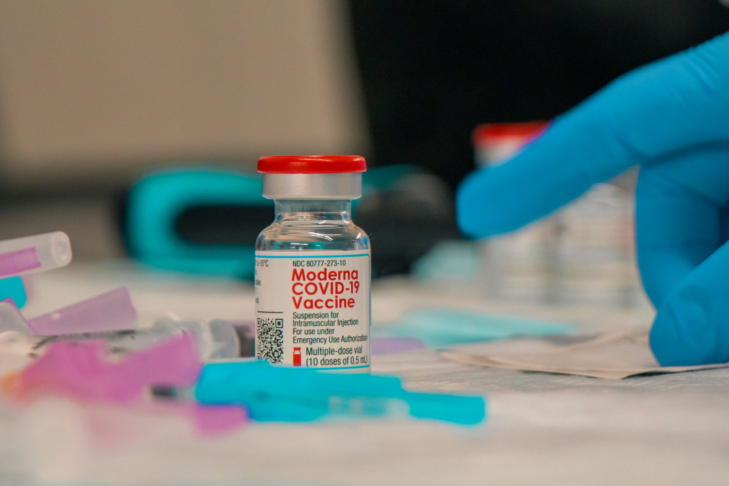 Vials of the Moderna COVID-19 Vaccine sit on a table inside the Community Event Building as caregivers with Providence Southwest prep syringes at the Southwest Washington Fairgrounds during a vaccine distribution event last January.