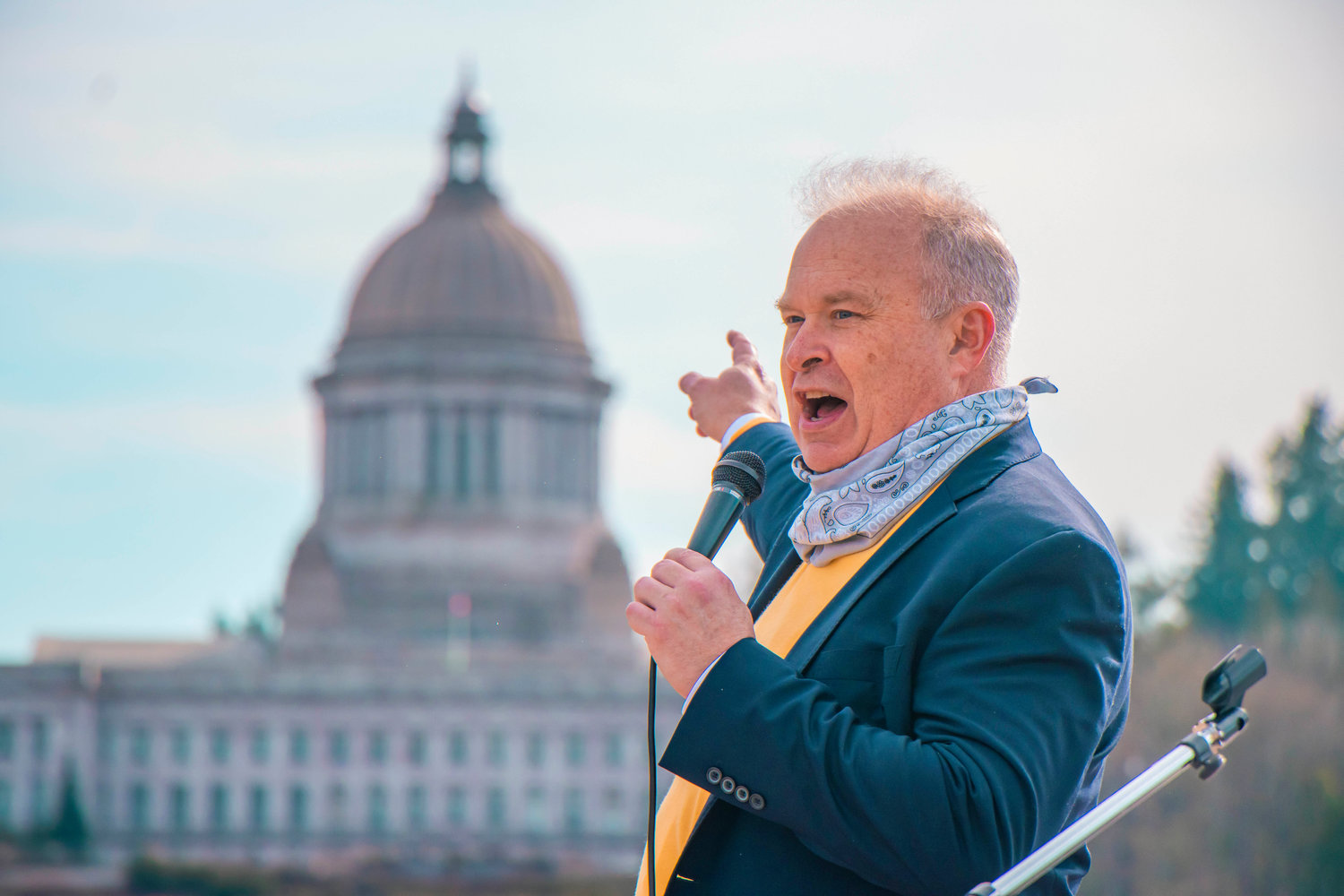 FILE PHOTO — State Rep. Jim Walsh points to the Washington State Capitol during a rally in support of bringing back in-person schooling near Capitol Lake.