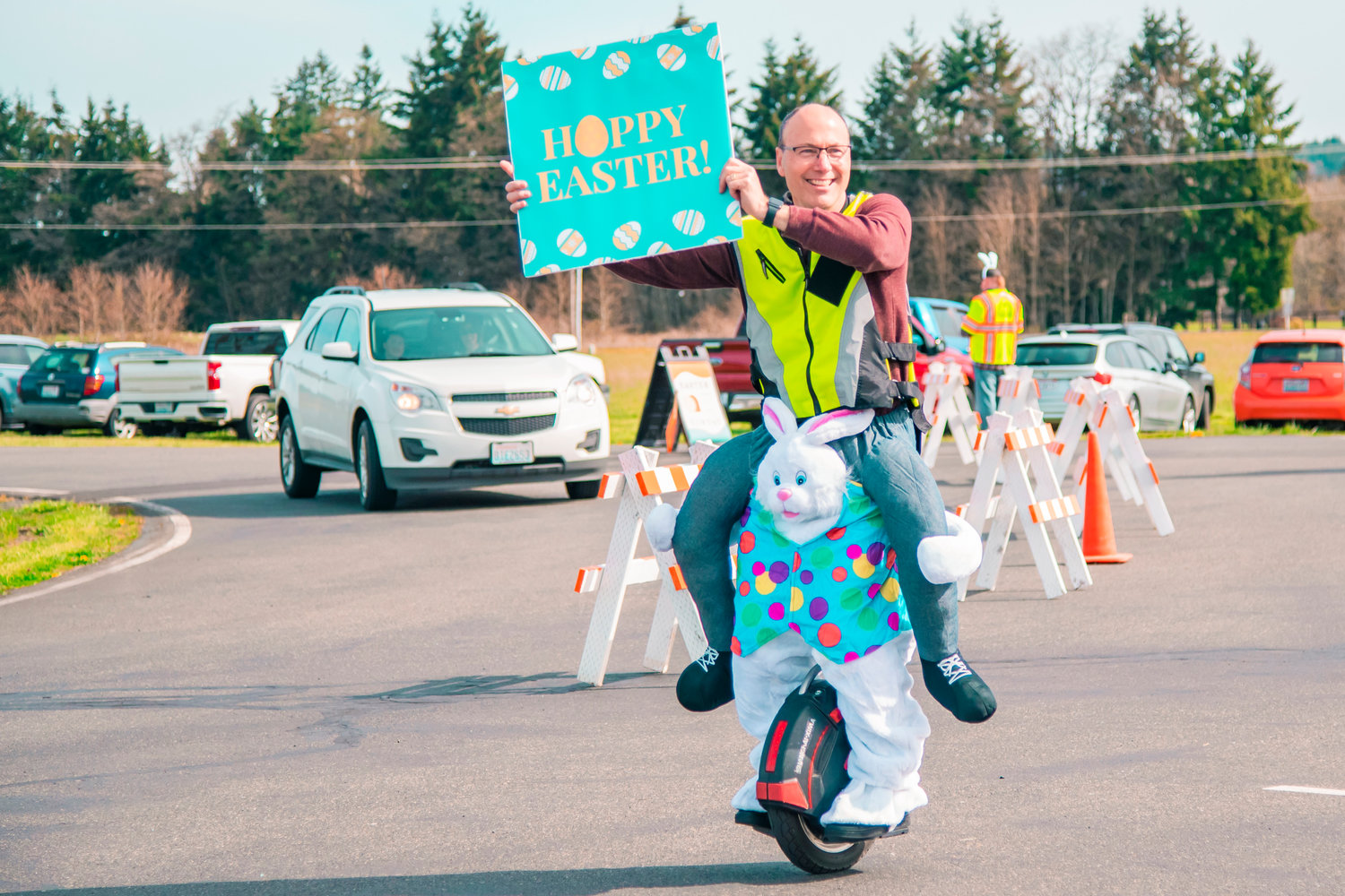 Kyle Rasmussen smiles while riding a one-wheel and holding a sign during an Easter event at Bethel Church in Chehalis on Saturday.