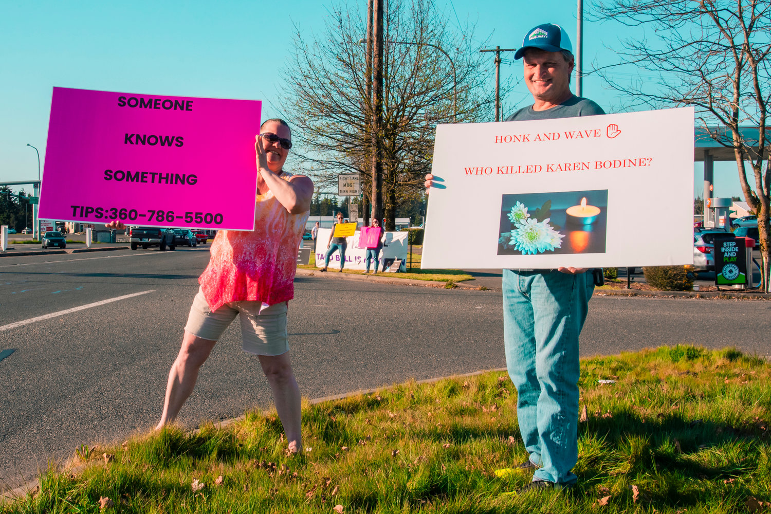 Colleen Eshom and Everett Bartlett hold signs during a honk-and-wave event for Karen Bodine and others in Grand Mound on Saturday.