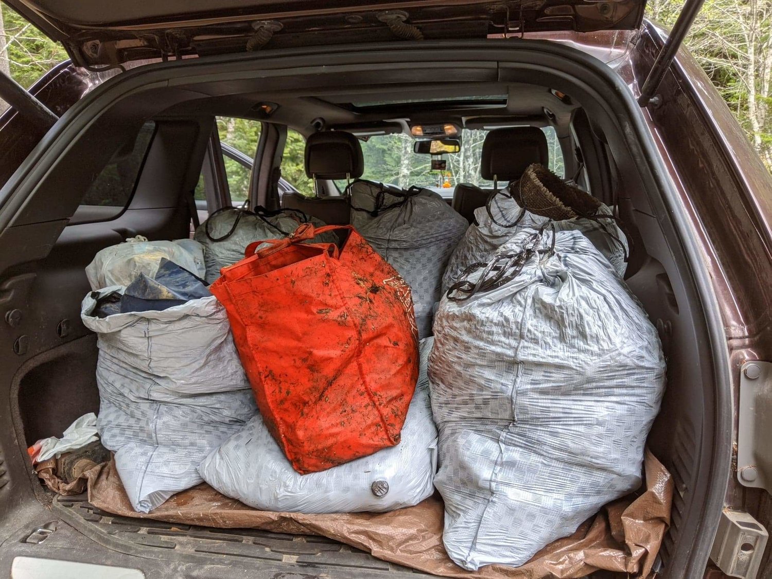 Trash bags are stuffed inside the back of a volunteer’s vehicle during a cleanup.