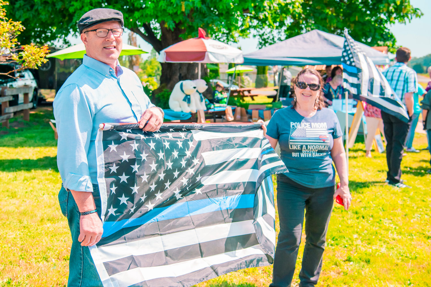 Stephen and Kathleen Kvavle smile while holding a “Thin Blue Line” flag in Adna on Saturday. The “Back the Blue” event was held at Adna Grocery and featured food, live music, merchandise and more.  It was held from 11 a.m. to 4 p.m. and coincided with the opening of a new burger bar by Adna Grocery owner Jim Smith.