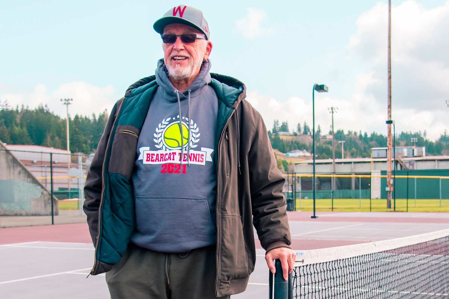 Jack State smiles as he talks about his years as a coach at W.F. West while standing on one of the school tennis courts.