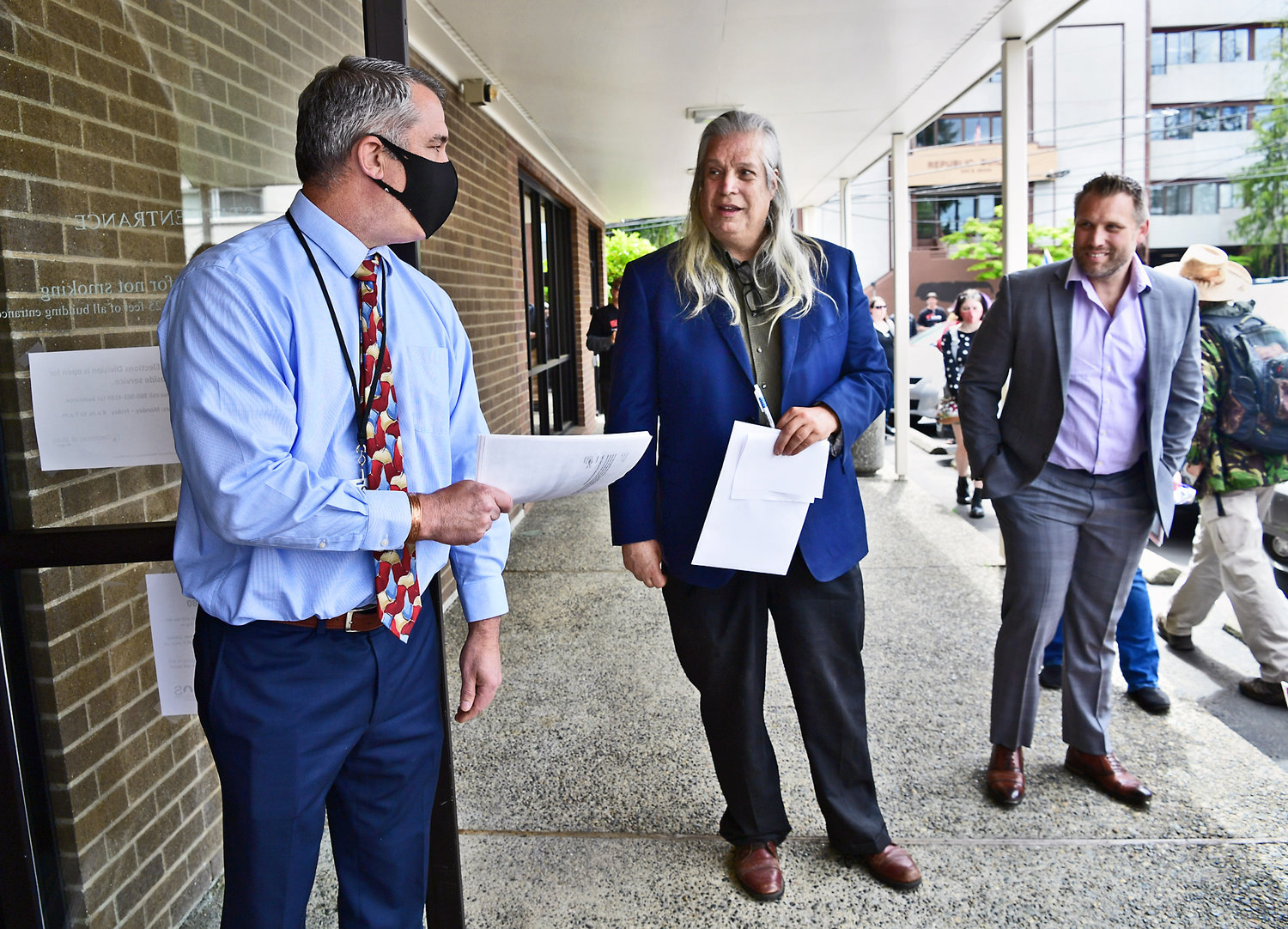 Olympia political activist C Davis, center, and Pasco attorney Pete Serrano, right, speak with Mark Neary, left, assistant secretary of state, in Olympia on Monday, May 17, at the Secretary of State’s Office after filing a petition for recall against Washington Gov. Jay Inslee on behalf of the organization Washingtonians to Recall Inslee.