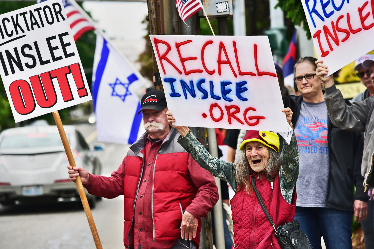 Yelm resident Bronwen Dickinson, middle right with red vest, shouts with glee at honking cars on Union Avenue during a gathering in Olympia on Monday, May 17, at the Secretary of State’s Office to file a petition for recall against Washington Gov. Jay Inslee. Dickinson was among about 100 people to attend the rally.