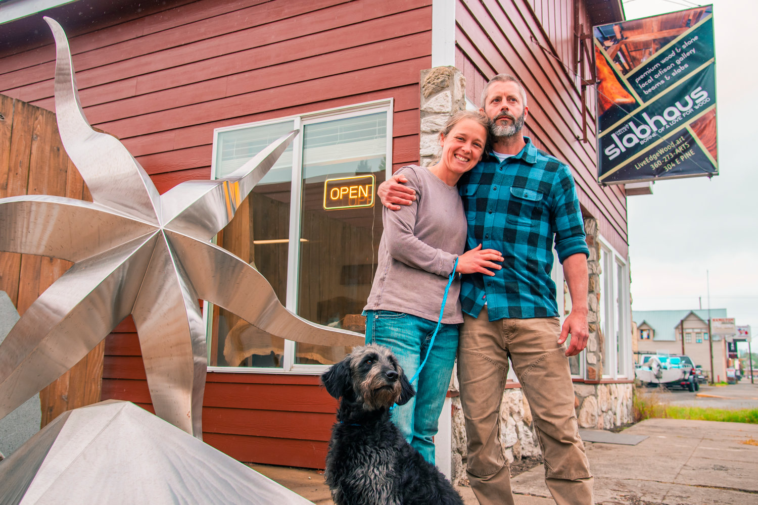 Tony and Shanna Hawes pose with their dog in front of the Chehalis Valley Slabhaus Sunday in downtown Oakville.