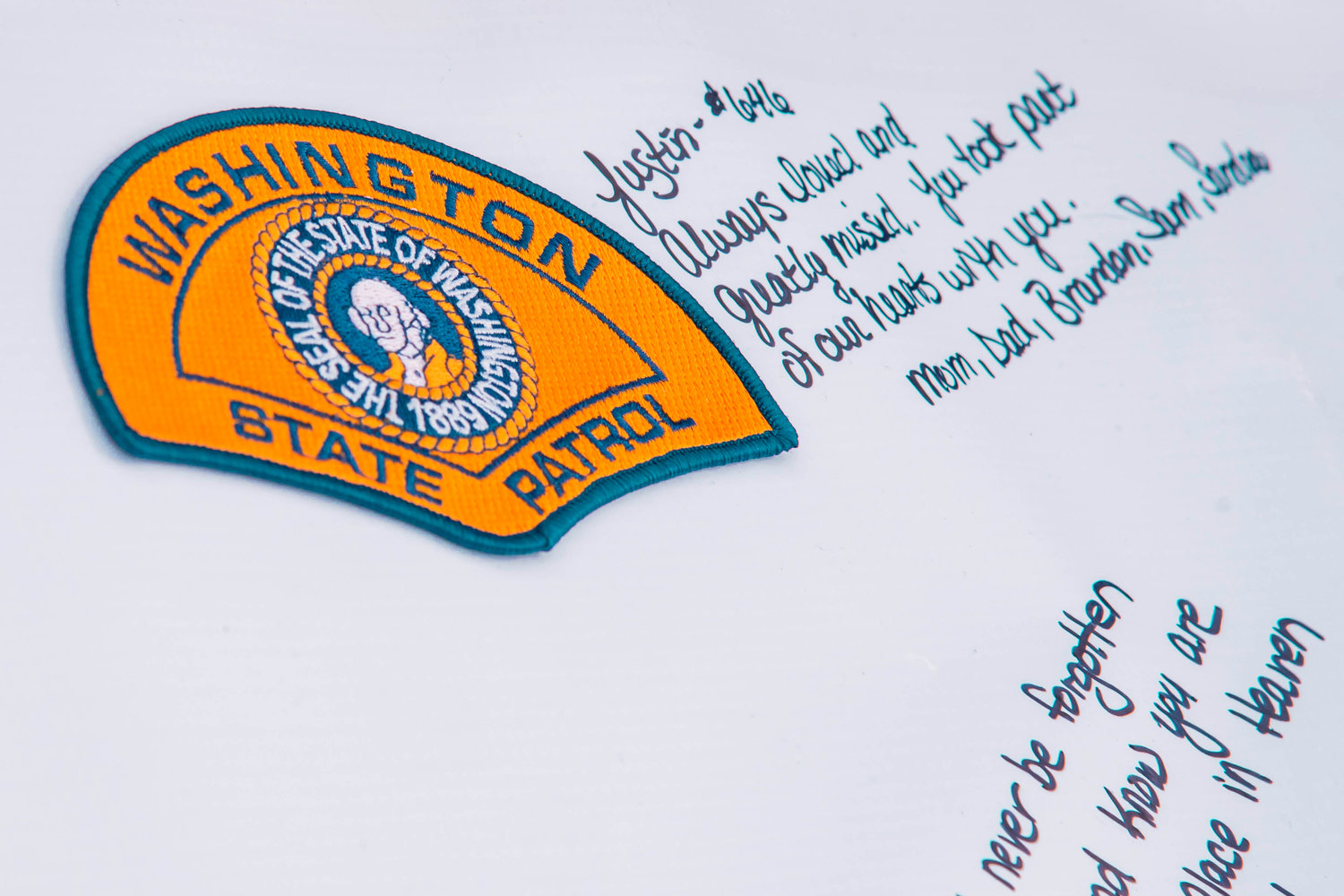 A Washington State Patrol patch is displayed on a board next to a message written by family during a memorial ride for fallen trooper Justin R. Schaffer.