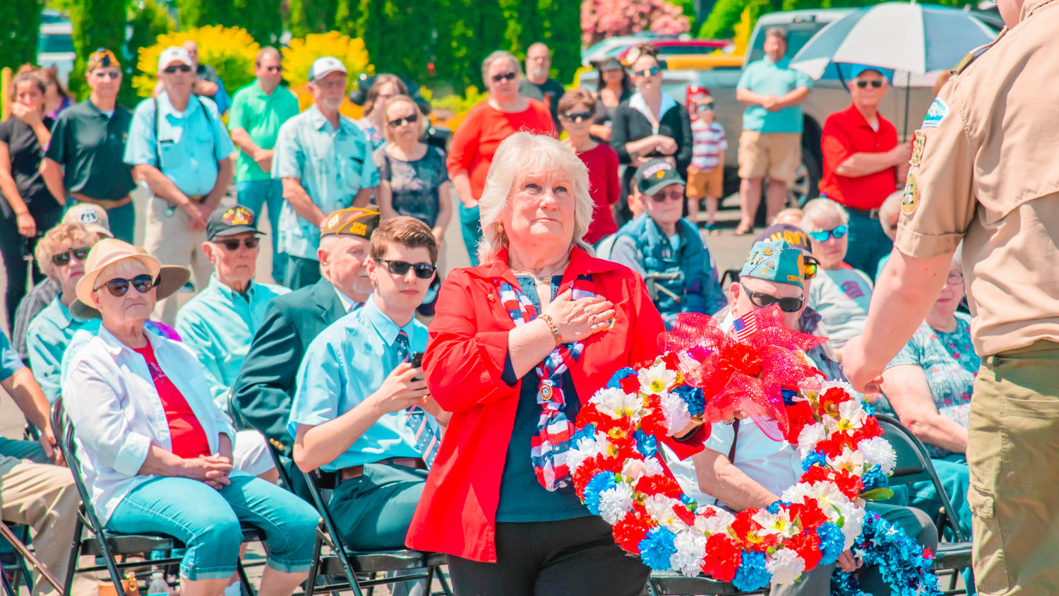 Glenda Thomas holds her hand over her heart as she hands a wreath to a scout to be placed at the base of a flag pole outside the Veterans Memorial Museum Monday afternoon in Chehalis as part of a Memorial Day ceremony.