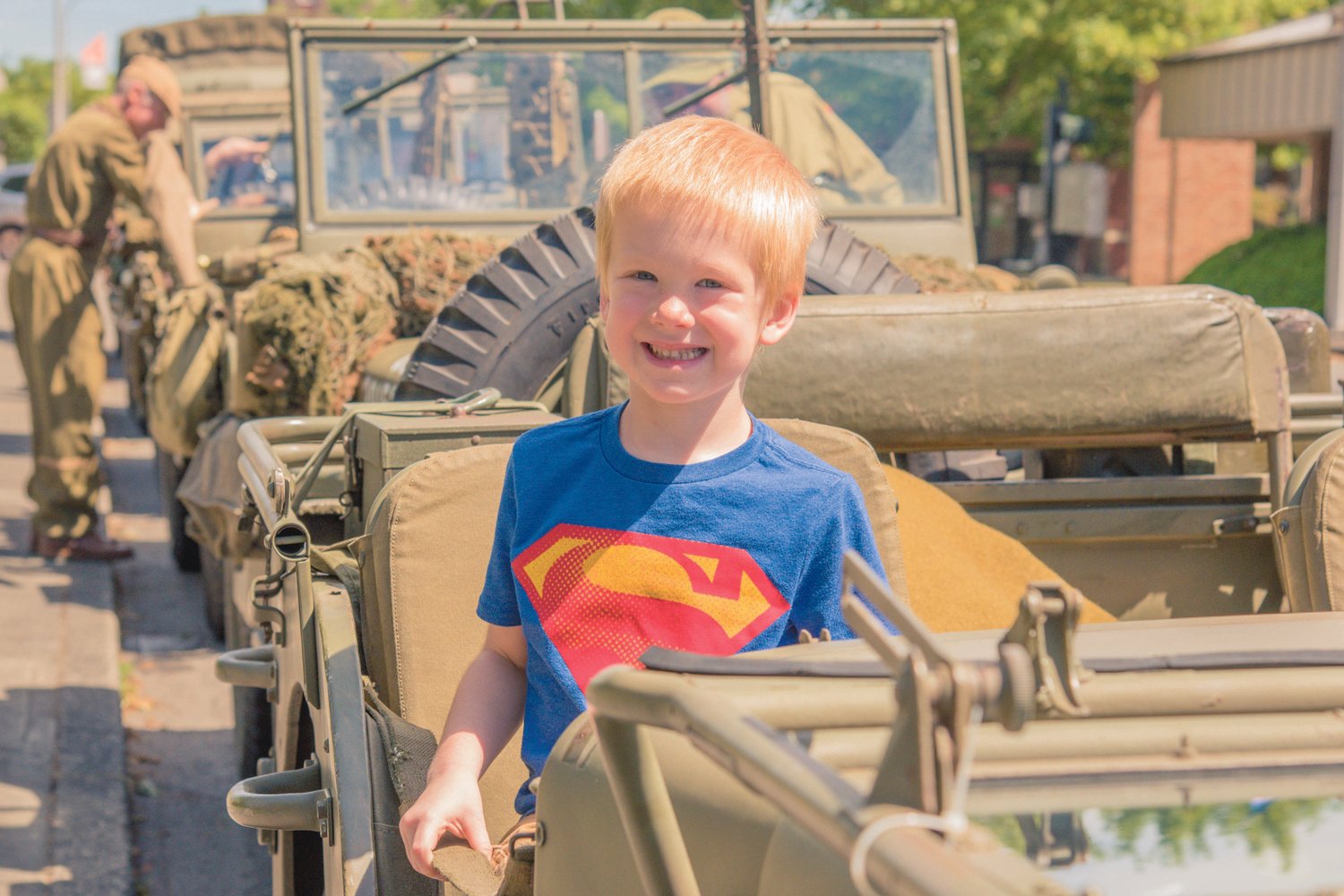 Hunter Myhre, 5, smiles as he sits in a World War II style vehicle Monday morning on Memorial Day.