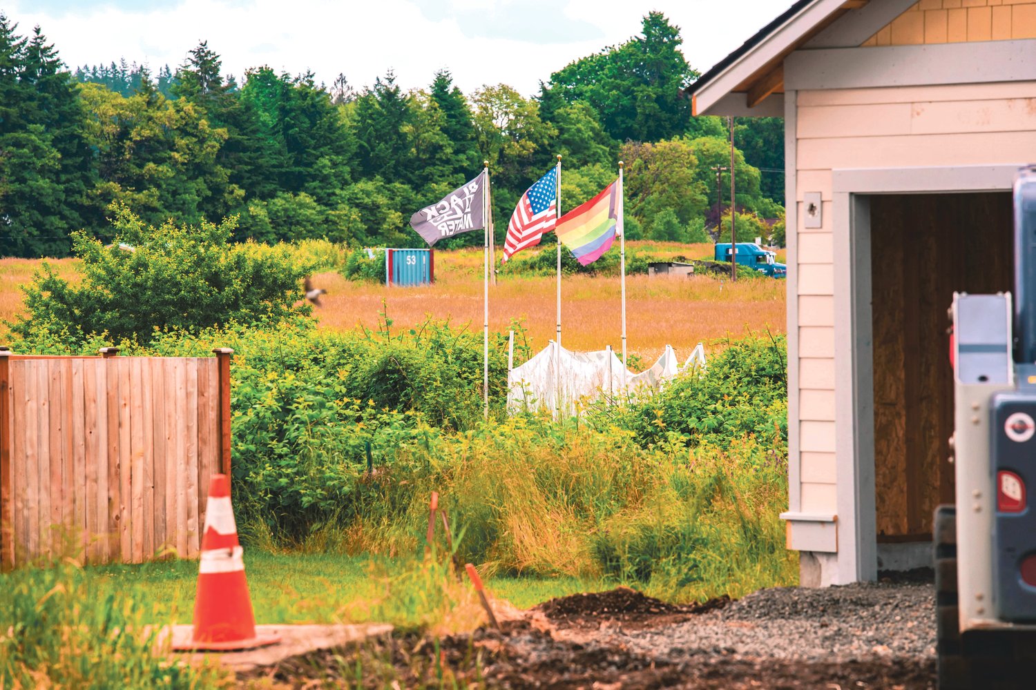 Flags on the Lewis County Lollipop Guild’s property wave between homes on Monday. In a lawsuit, Lollipop Guild founder Kyle Wheeler alleges that local governments have favored Scott Marvin’s Marvin Construction, LLC, which has “repeatedly encroached” and “continually trespassed” on his single-acre property.