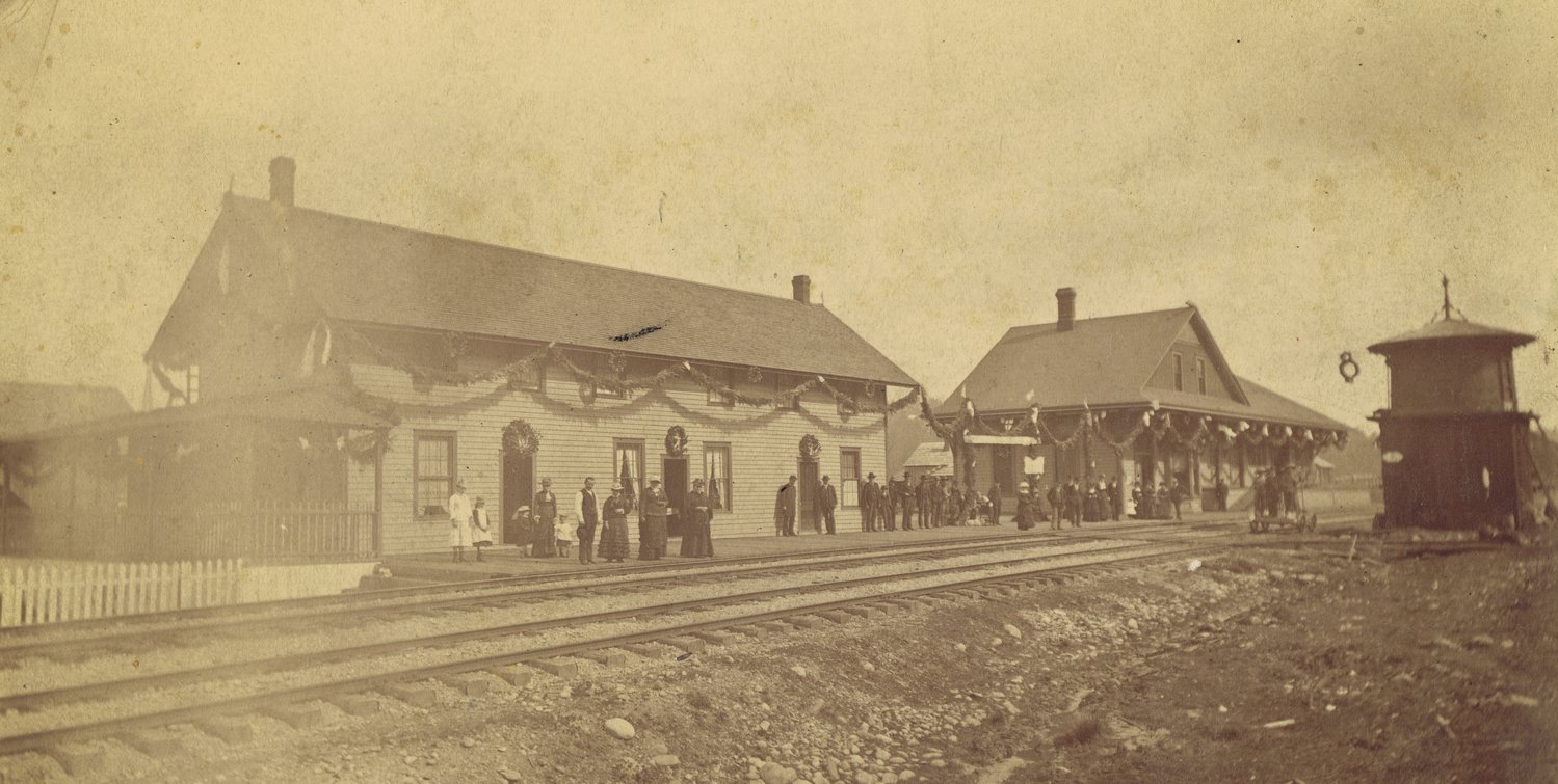 This photo was previously held as the earliest known photo of Tenino. It depicts the hotel and train depot. According to Tenino City Historian Richard Edwards, in 1883 the Northern Pacific Railroad declared their transcontinental line finished. In celebration, the company took the train from Chicago to Seattle, stopping at every depot along the way. Depots decorated for the occasion. In the photograph, the banner seen next to the depot and the garlands hanging from both buildings match those used by Tenino for that celebration.