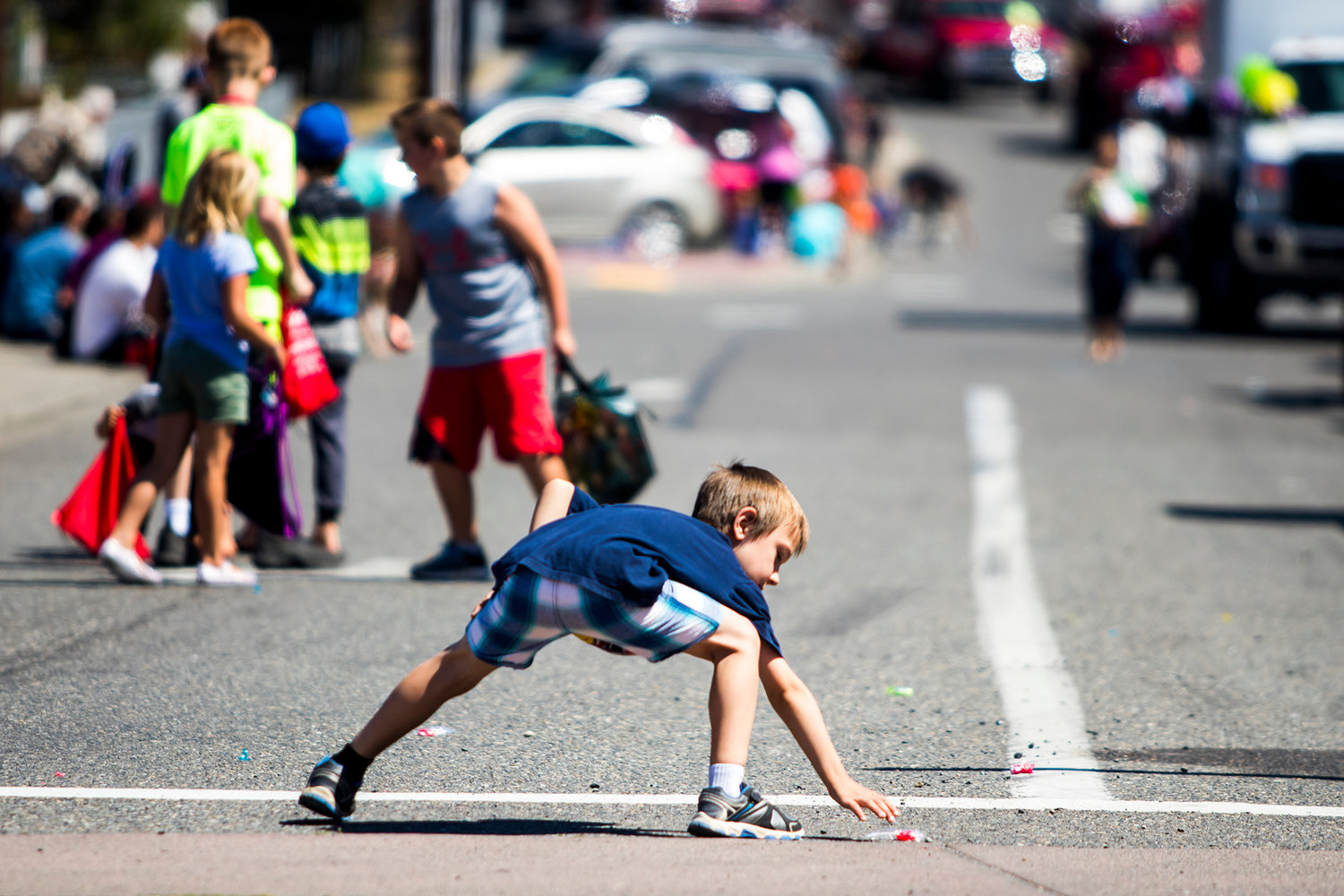 A kid stretches out to grab a piece of candy from the roadway during the annual Funtime Parade in 2018.