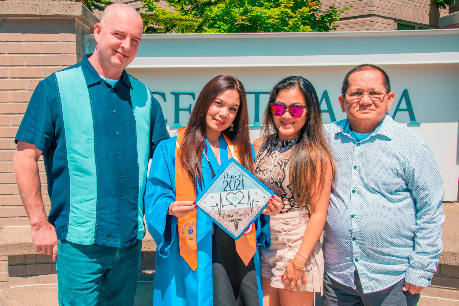 Praise Paradis hols up her decorated cap while posing for a photo in front of the Centralia College sign during a graduation ceremony held on Friday.