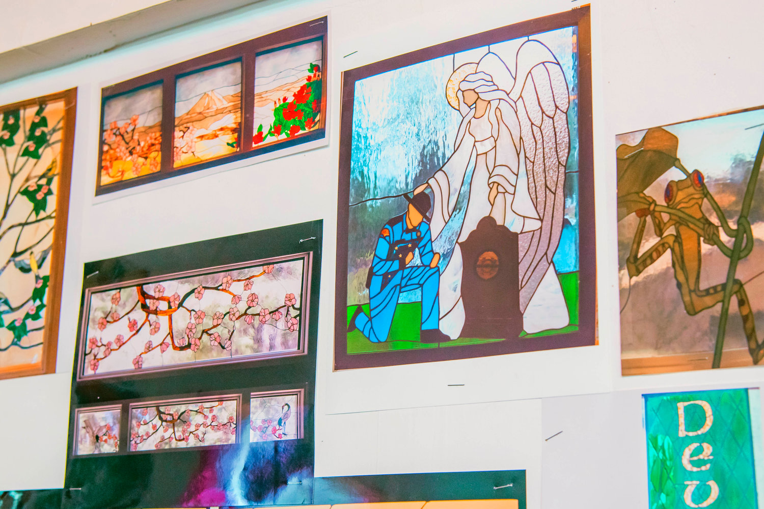 Images of stained glass pieces hang on display inside Marcy Anholt’s studio.