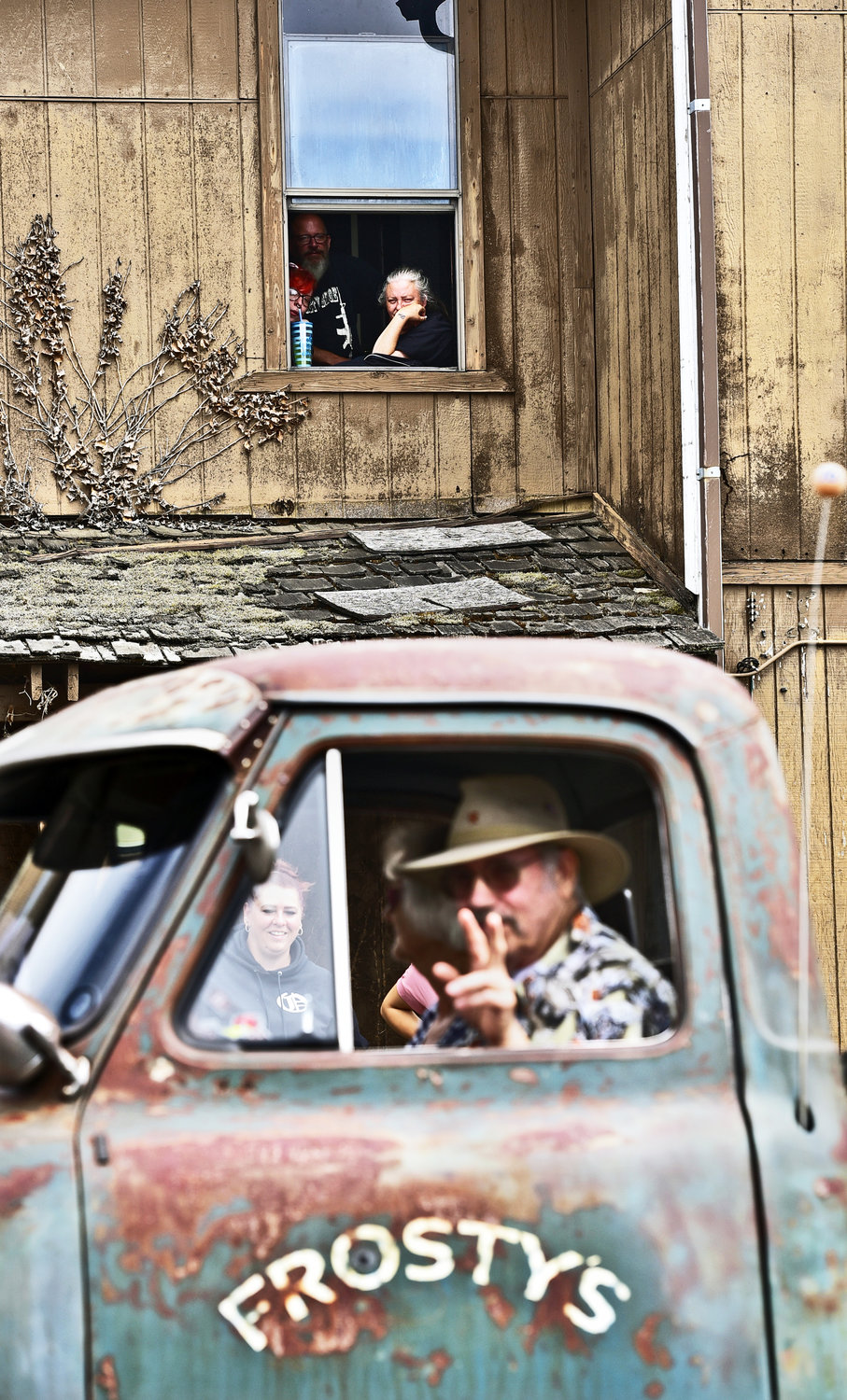 From their perch above Oakville’s main drag in what appeared to be a dilapidated building, a man and woman watch Oakville’s Independence Day parade on Saturday, July 3, as a parade participant signals from an old pickup truck.