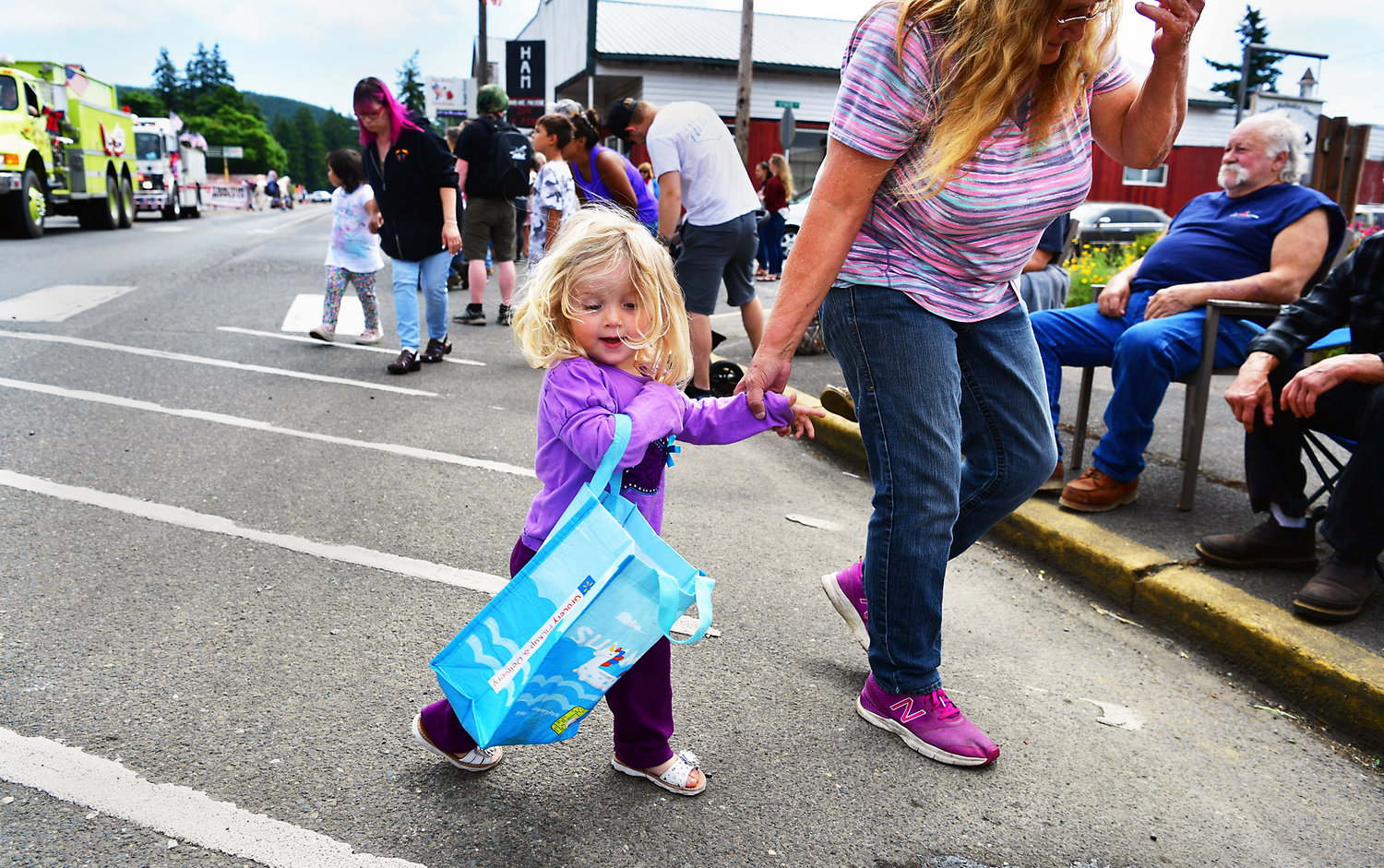Tenino resident Laiya Muxen, 2, had just grabbed some sweet goodies on the ground before her great-grandmother Nancy Ware, 63, from Rochester, led her back to the curb during Oakville’s Independence Day parade on Saturday, July 3.
