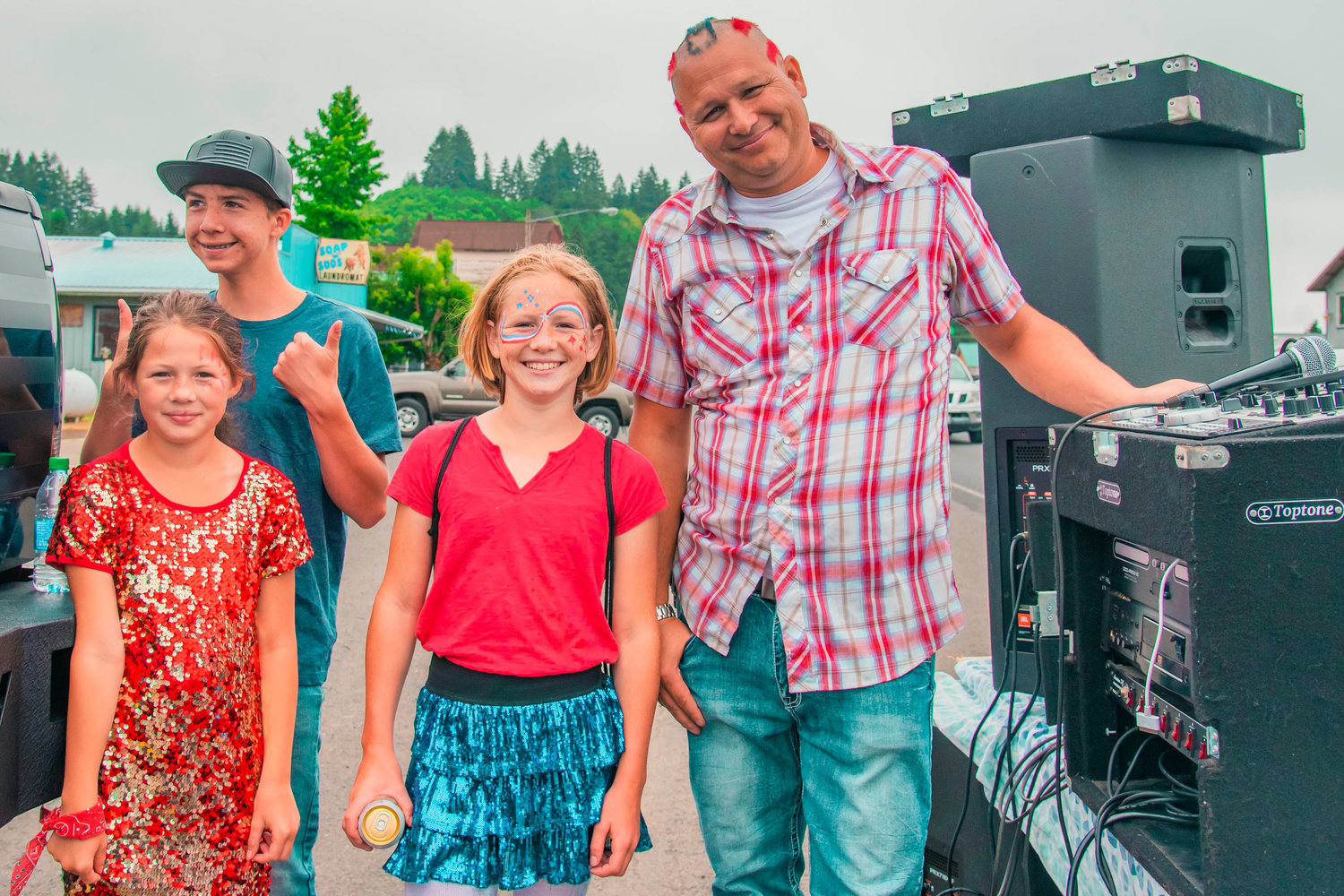 DJ Spider Mann and kids pose for a photo following the Freedom Festival parade on Saturday along East State Street in downtown Mossyrock.