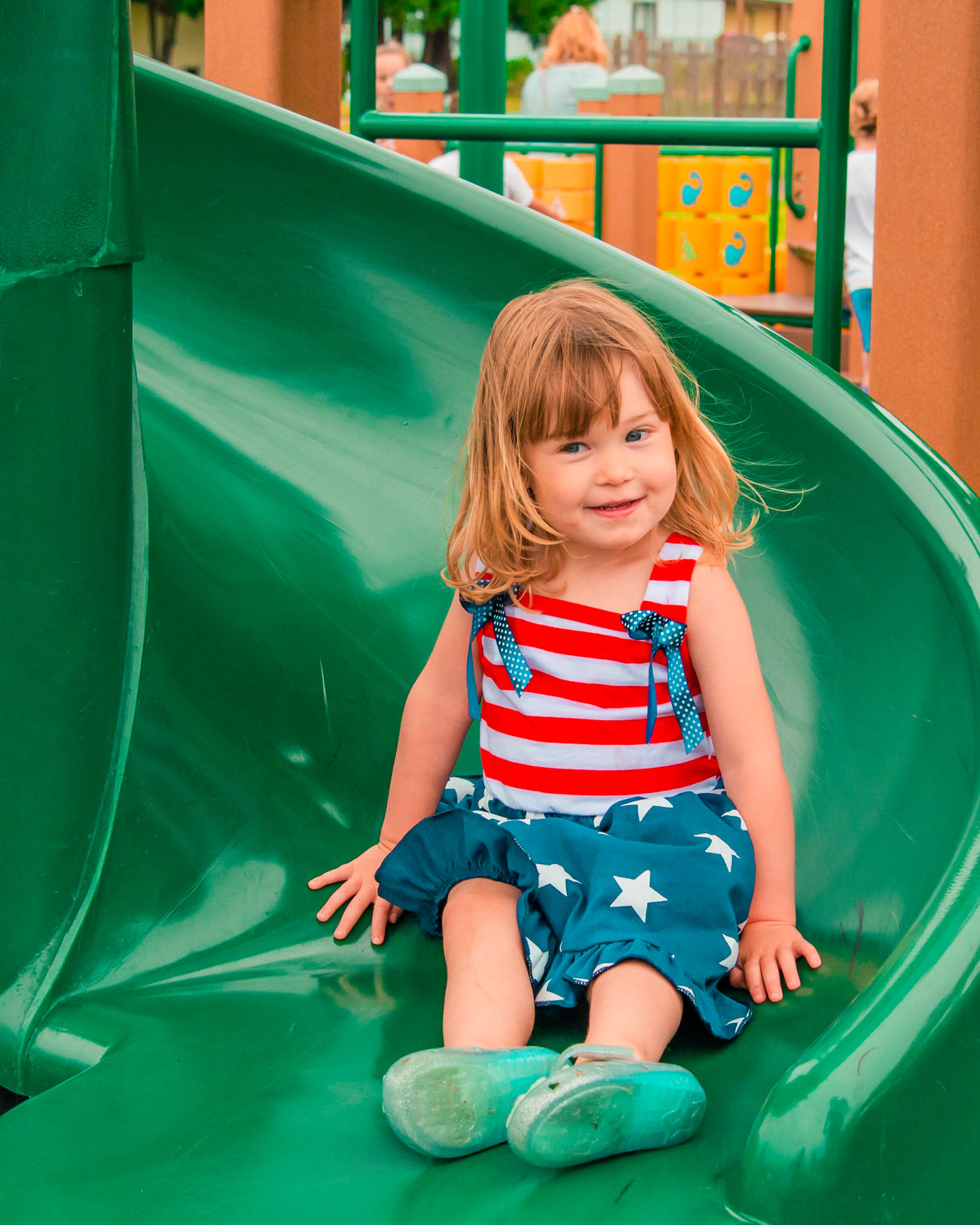 Charlie Grant, 2, smiles as she comes down a slide in Klickitat Prairie Park sporting an American Flag-styled dress Saturday during celebrations for the Mossyrock Freedom Festival.