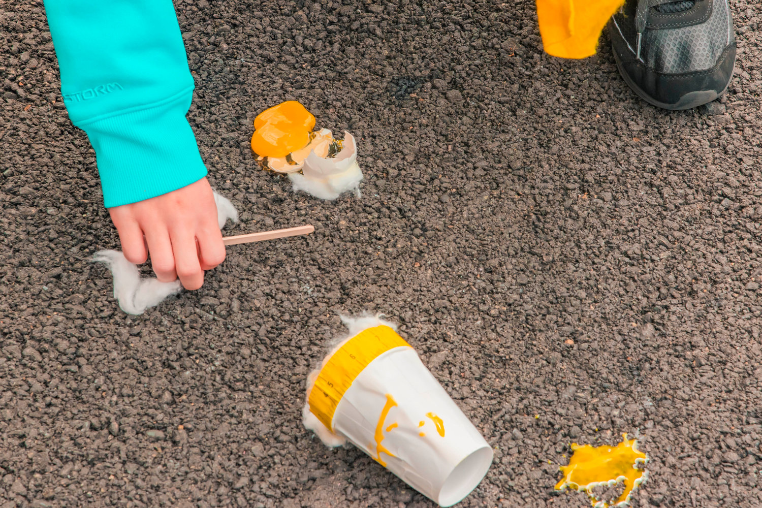 The remains of an egg wrapped in cotton are splattered on the ground next to a student in the Fords Prairie Elementary School summer program Thursday in Centralia.
