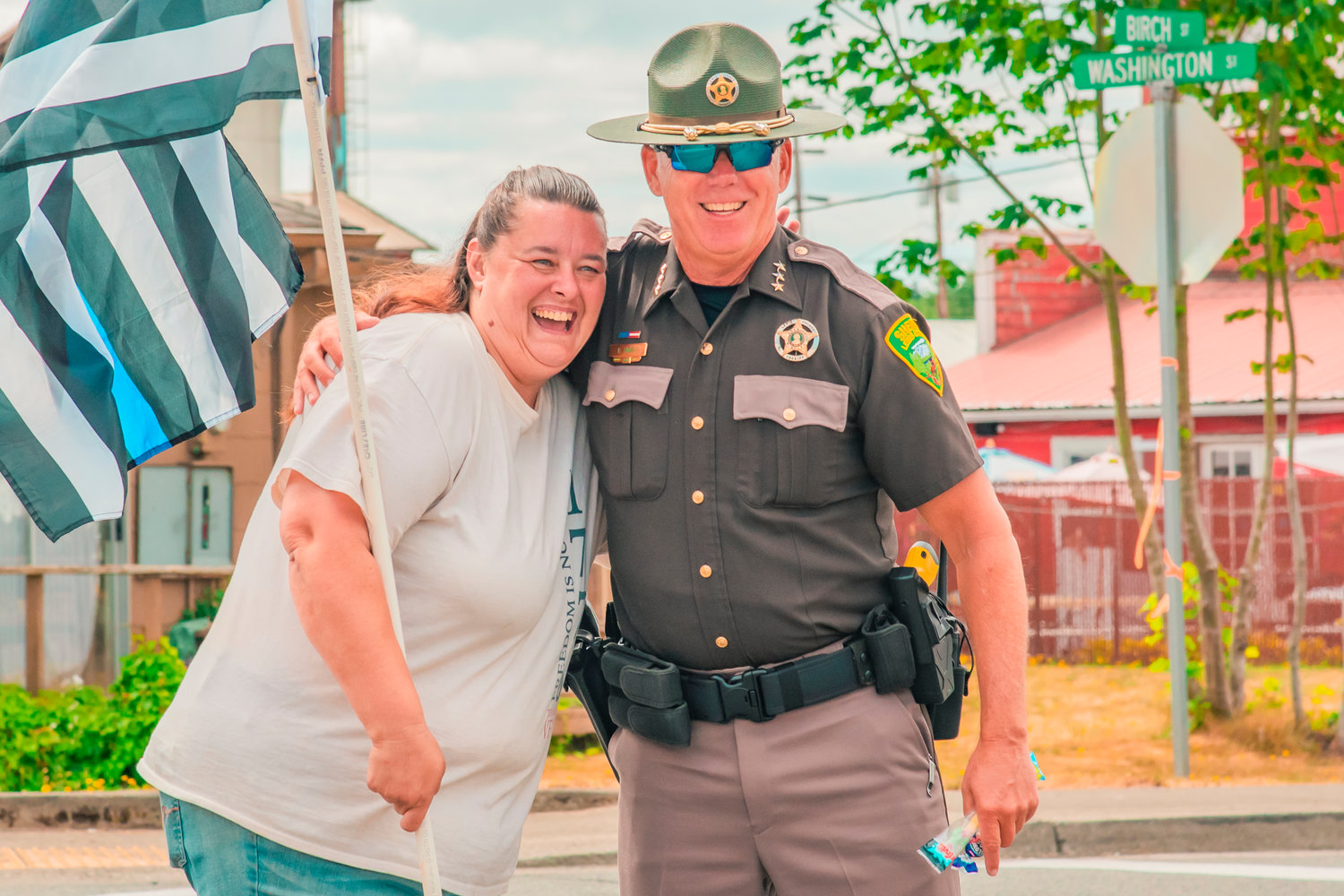 Dawn Miles smiles as she is stopped by Lewis County Sheriff Rob Snaza for a hug while carrying a “Thin Blue Line” flag on Saturday during the Napavine Funtime Festival parade.
