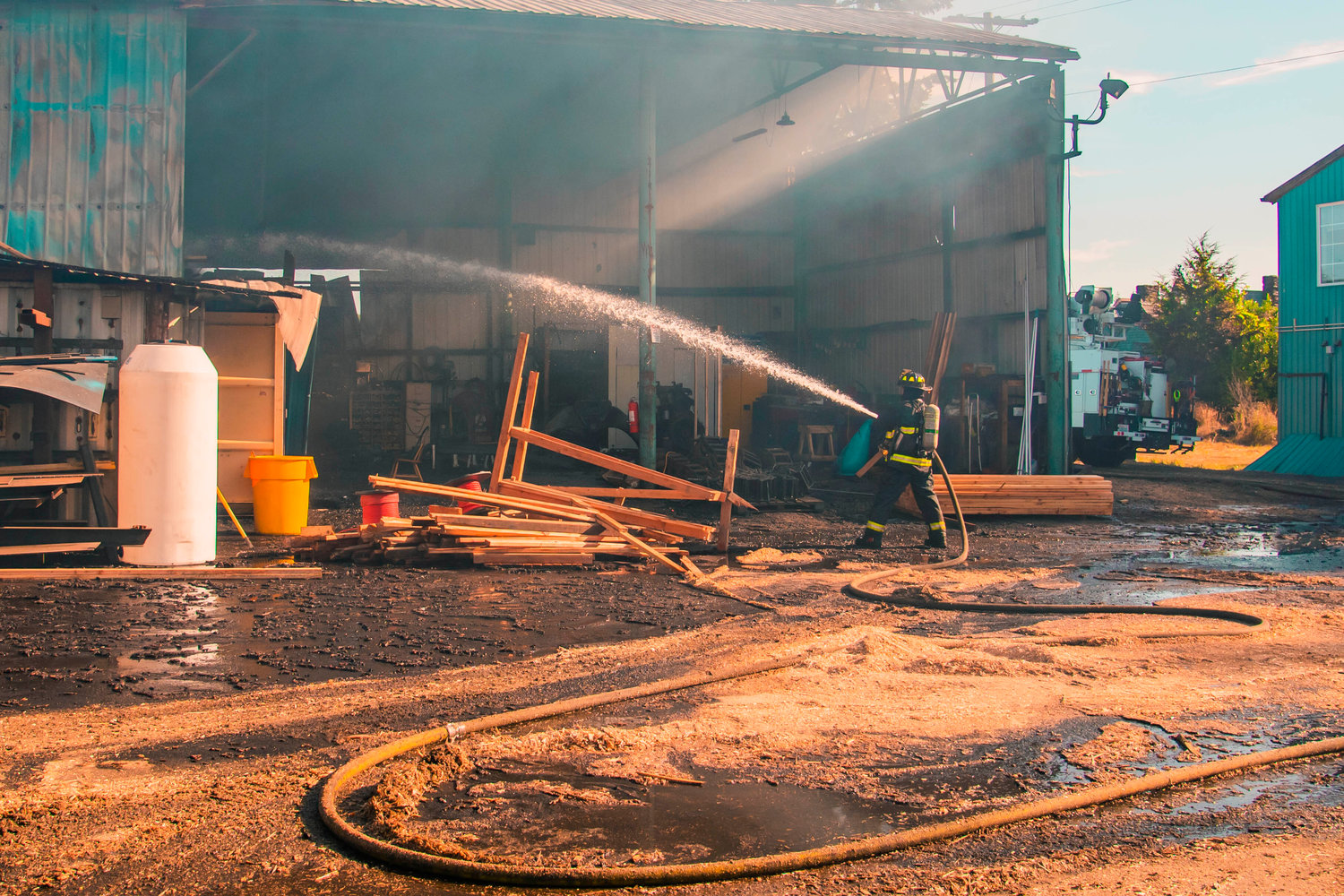 A Fire District 2 firefighter extinguishes hot spots with a hose at Winlock Fibre following a fire early Wednesday morning.