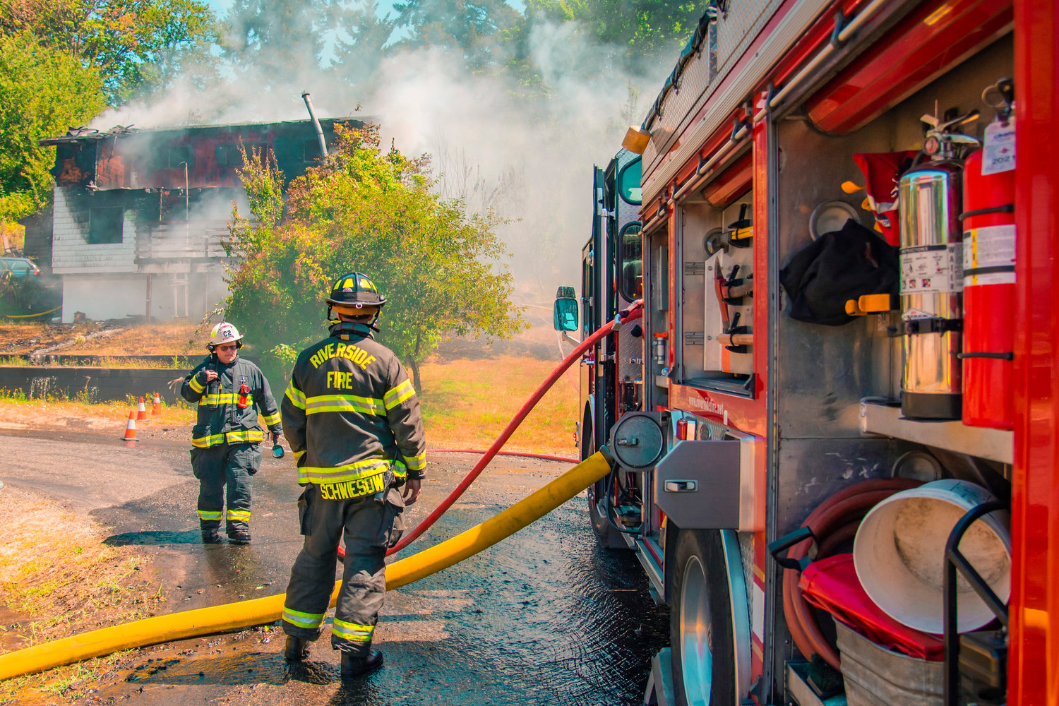 Riverside Fire Authority Assistant Chief Kevin Anderson works with firefighters to put out flames at a residential structure on East Third Street in Centralia on Thursday.