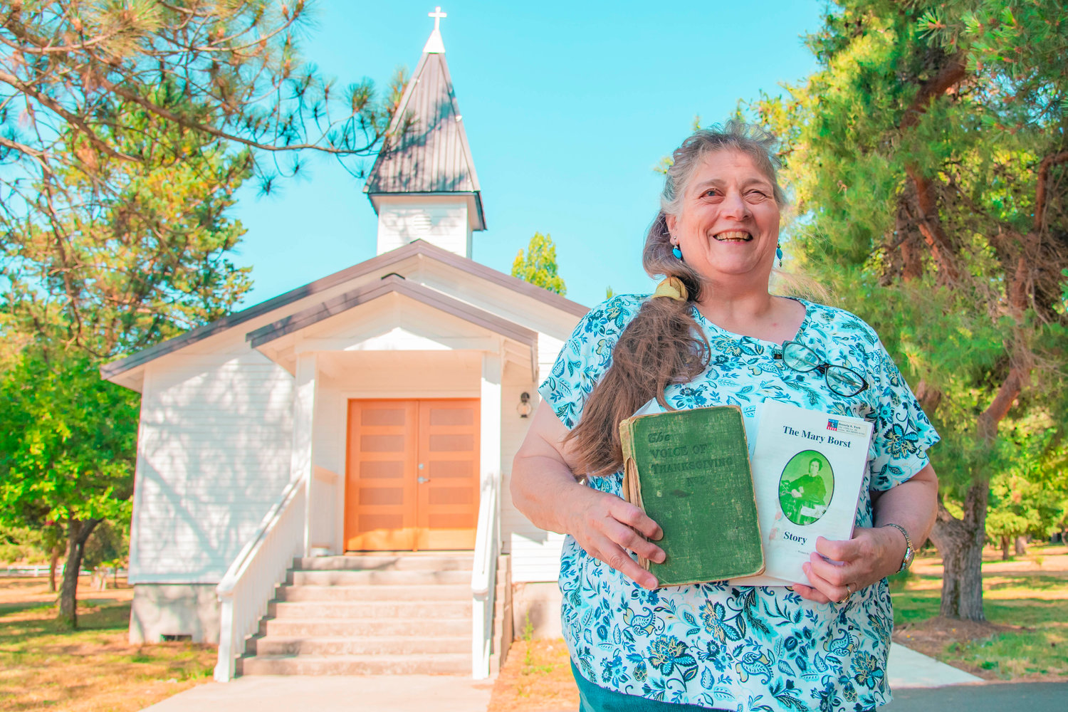 Beverly York smiles and poses for a photo in front of the Borst Park Pioneer Church Monday in Centralia.