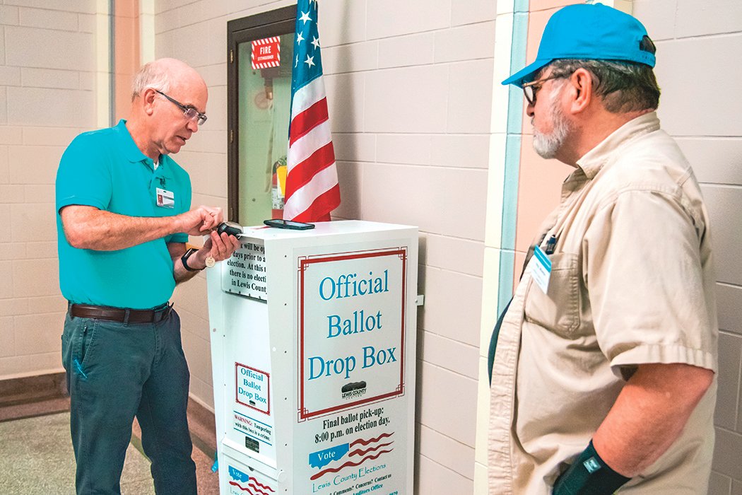 Neil Marsh looks on as Auditor Larry Grove locks an official ballot drop box on Election Day at the Historic Lewis County Courthouse in Chehalis last year.