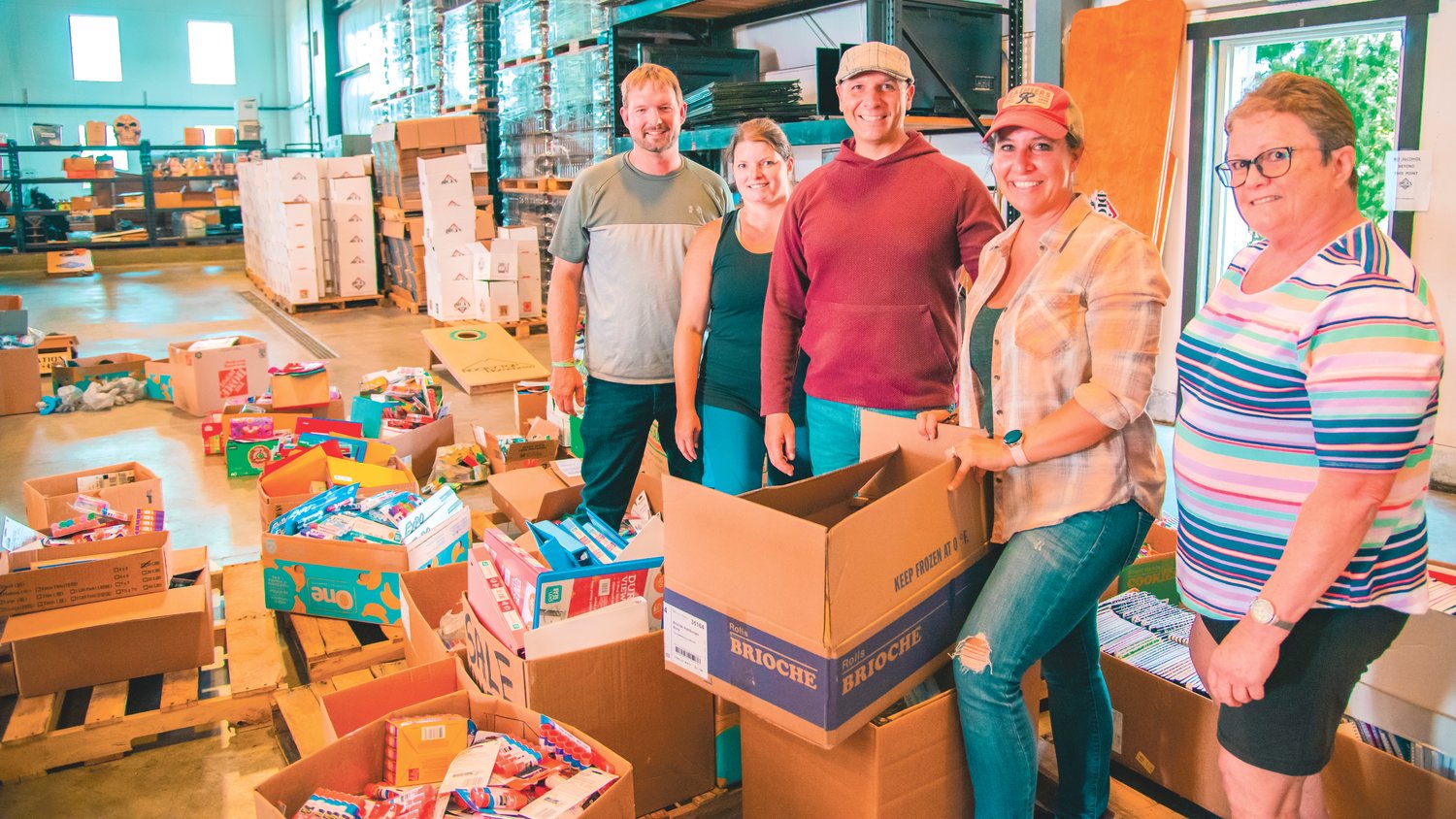 Left to right, Kyle Markstrom, Julie Pendleton, Peter and Holly Abbarno and Marilyn Gallagher pose for a photo while sorting boxes at Dick's Brewing in Centralia on Tuesday after unloading a bus full of school supplies from a 