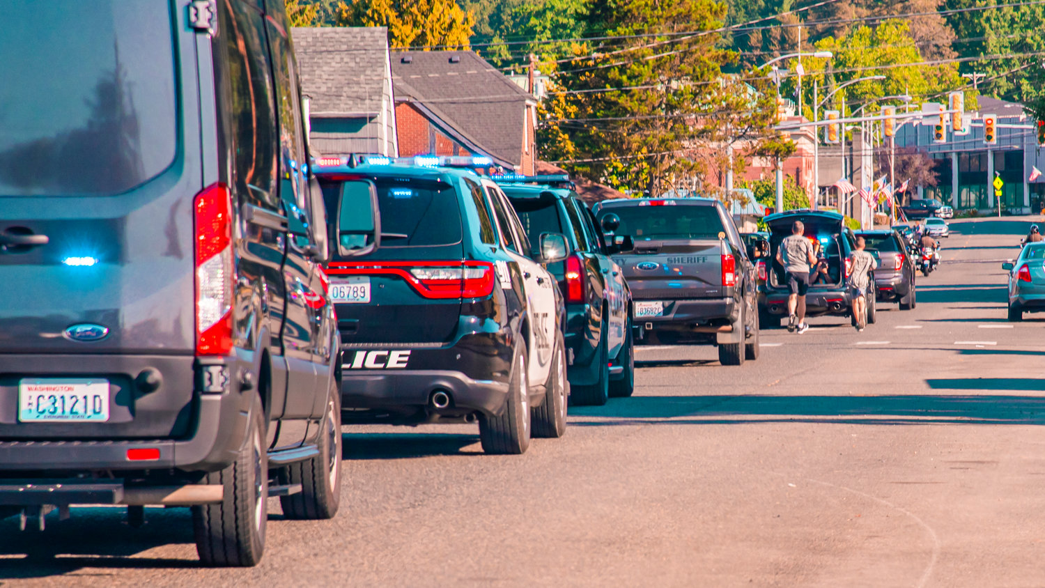 A procession of vehicles follows torch runners through downtown Chehalis during the Lewis County Law Enforcement Torch Run for the Special Olympics Saturday morning.