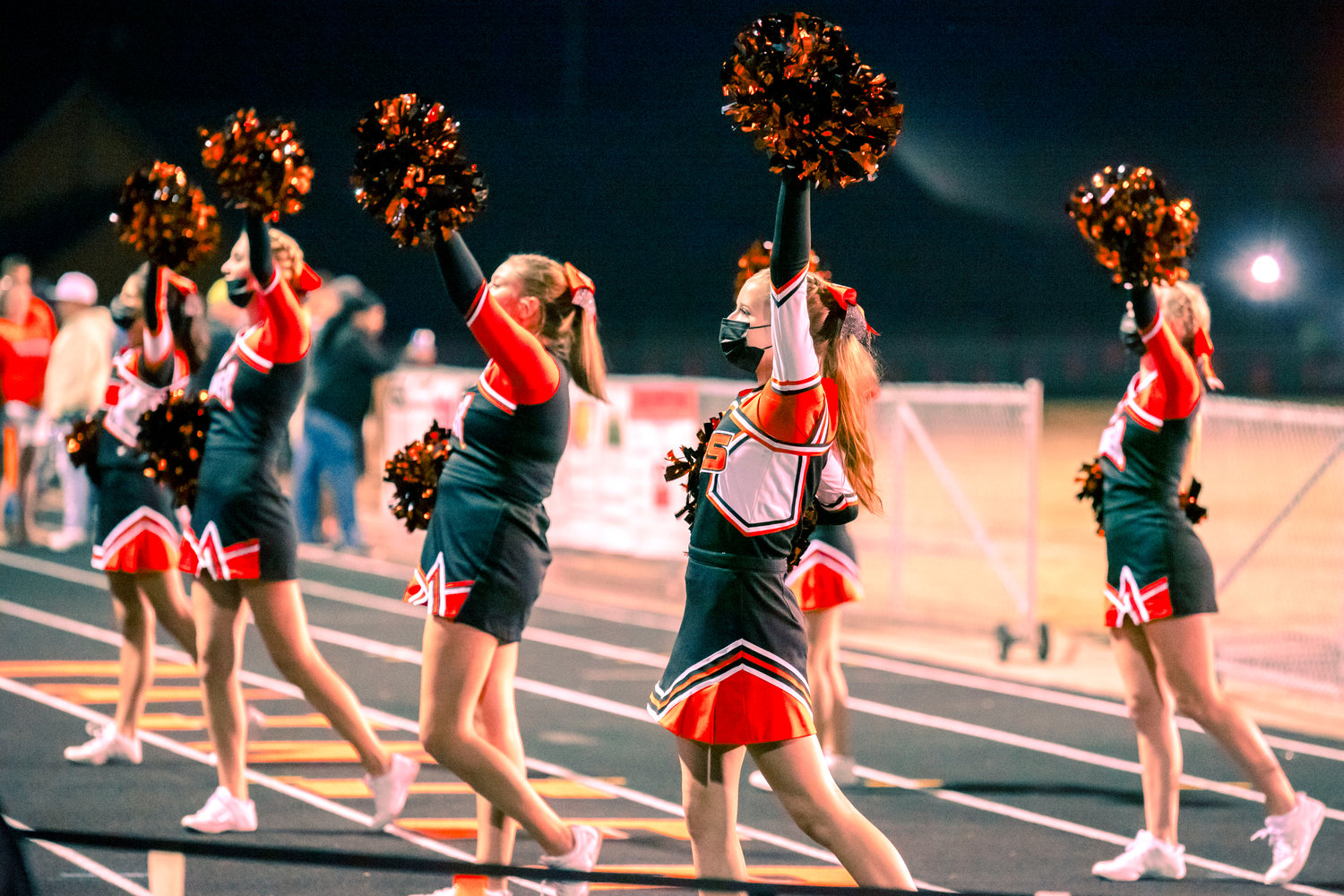Members of the Rainier High School Cheerleading Team raise their pom-poms during a game Friday night.