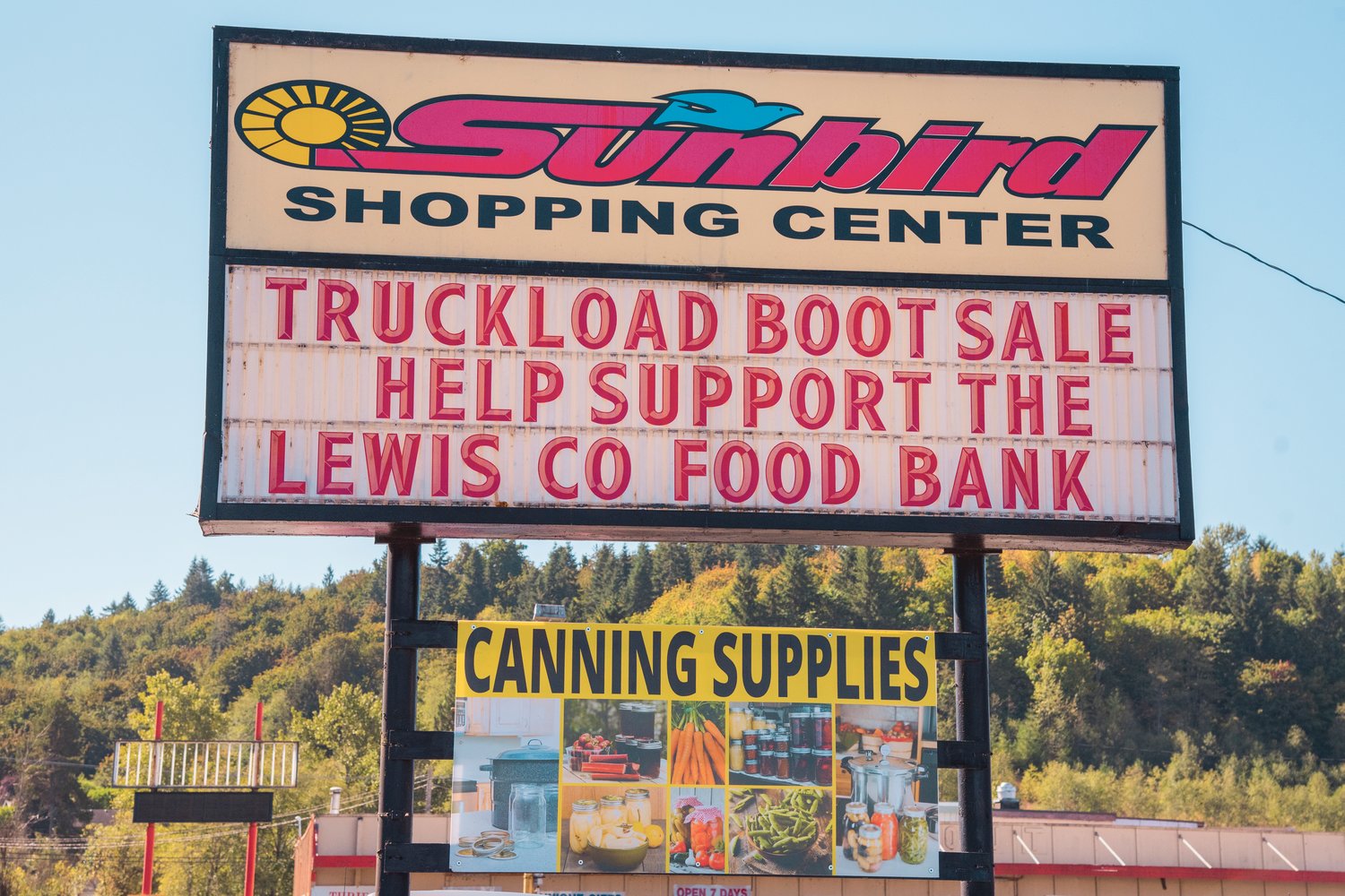 Signage for the annual "Truckload Boot Sale" is displayed at the Sunbird Shopping Center while the business donates $5 of every Georgia Boot sale to the Lewis County Food Bank.