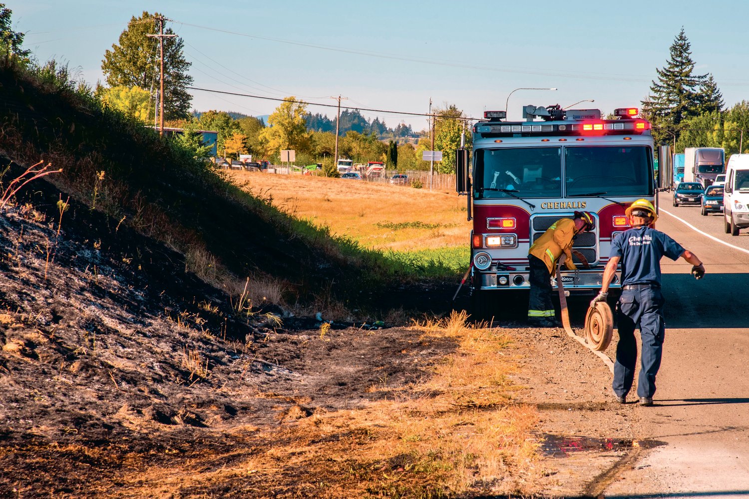 Chehalis fire crews pick up hose lines after responding to a call for a brush fire along the southbound lane of Interstate 5 near milepost 77 Tuesday afternoon.