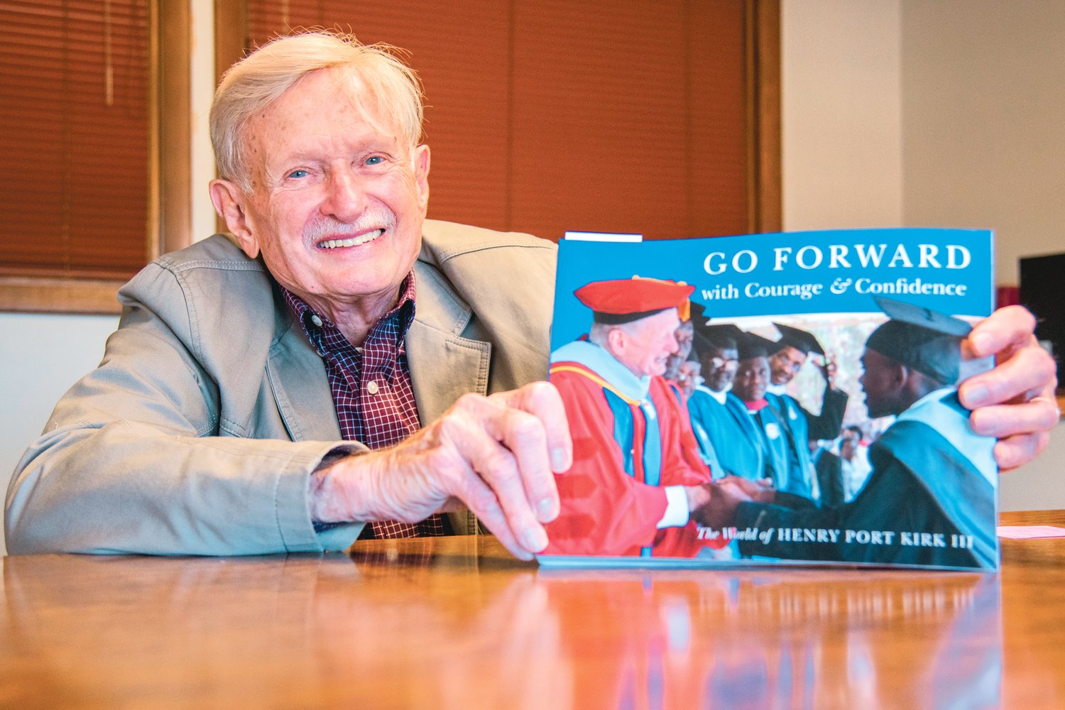 Henry Port Kirk III smiles and holds up his book "Go Forward with Courage & Confidence" Tuesday in Centralia.