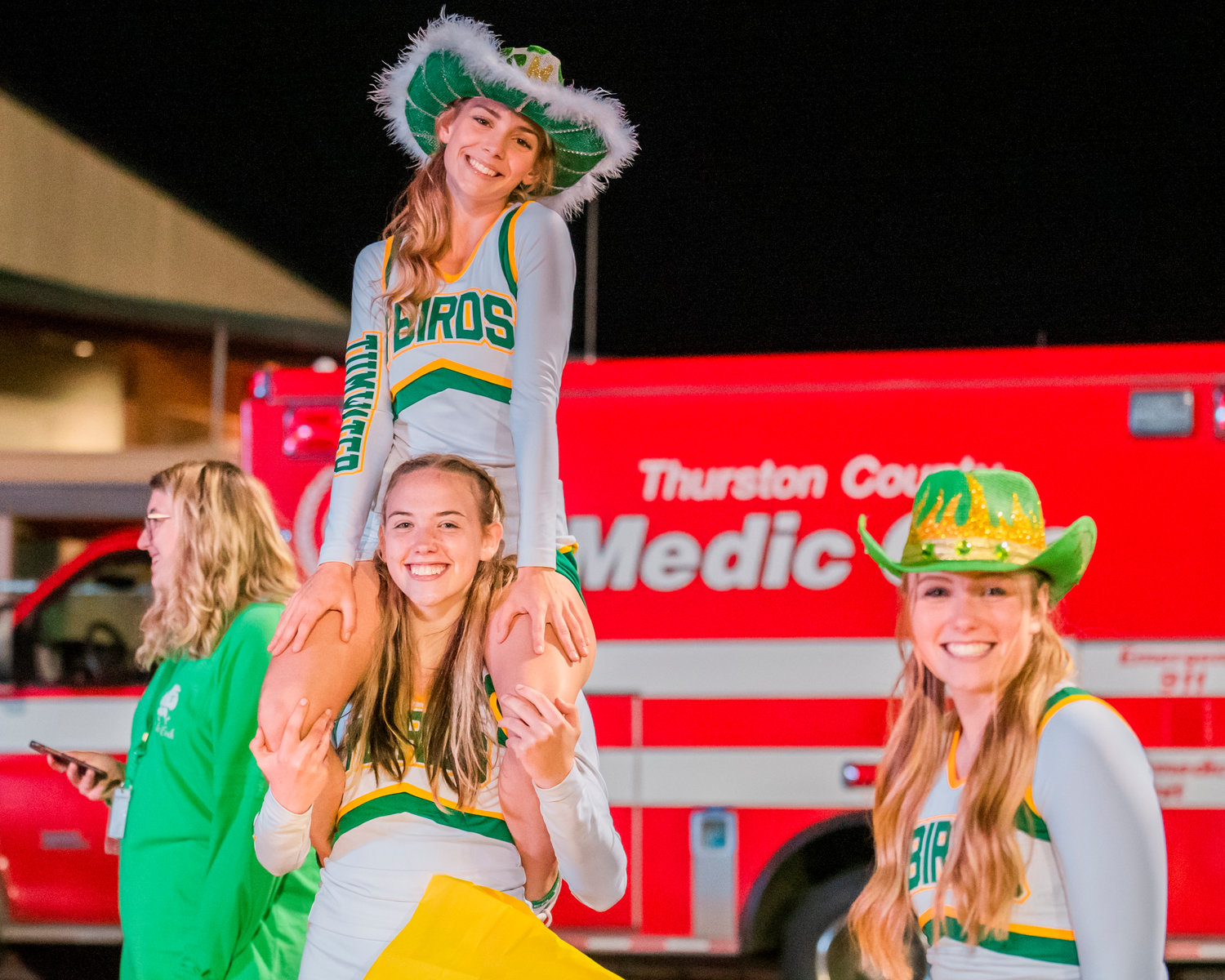 Tumwater cheerleaders pose for a photo while setting up the halftime team enterance during a Friday night game.