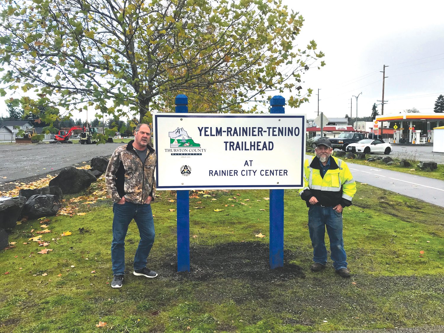 Rainier Mayor Bob Shaw and a worker show off the newly-installed Yelm-Rainier-Tenino Trail sign at the Rainier trailhead.