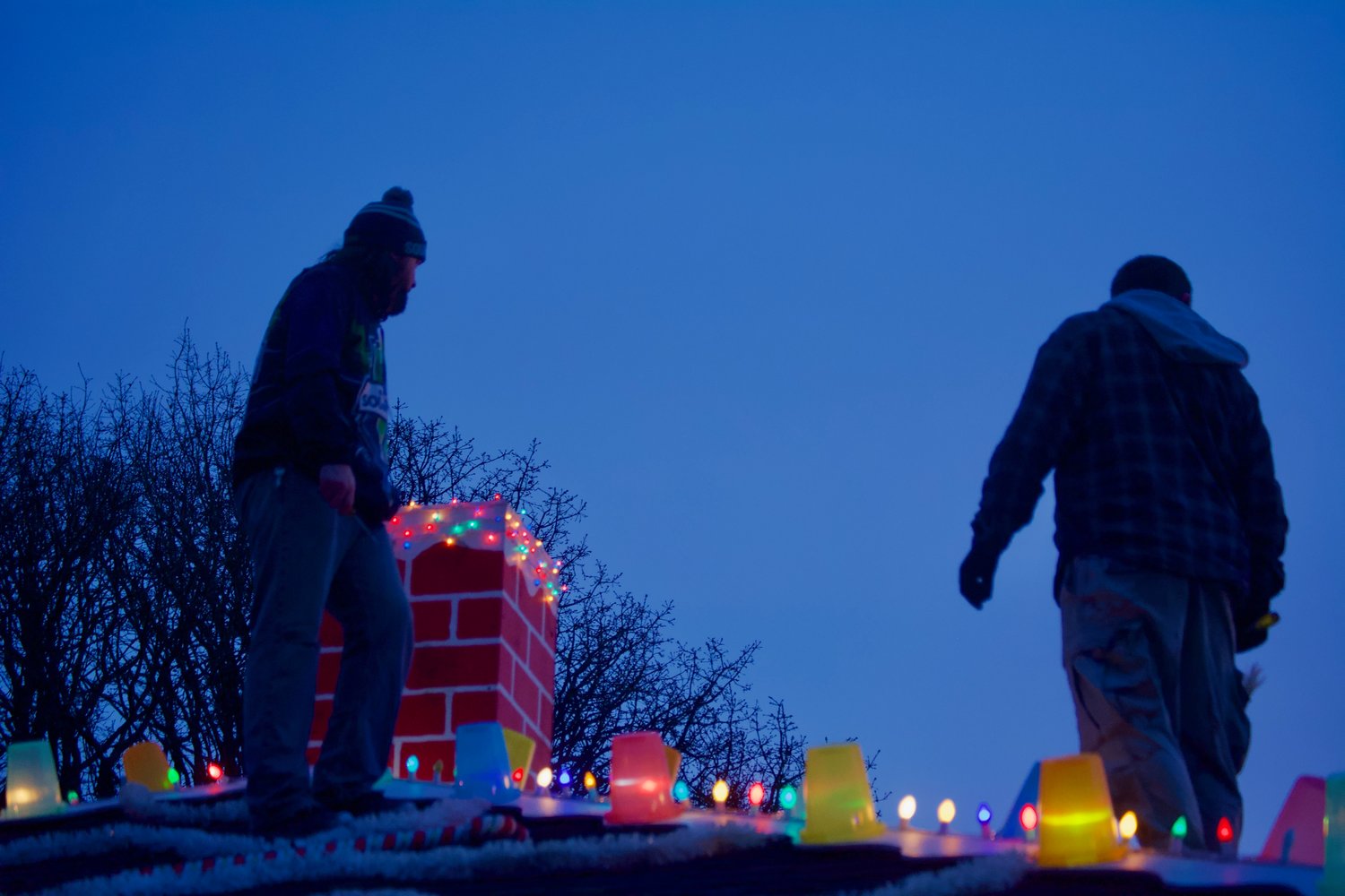 Workers stand atop the roof of the gingerbread house in Chehalis on Saturday evening.