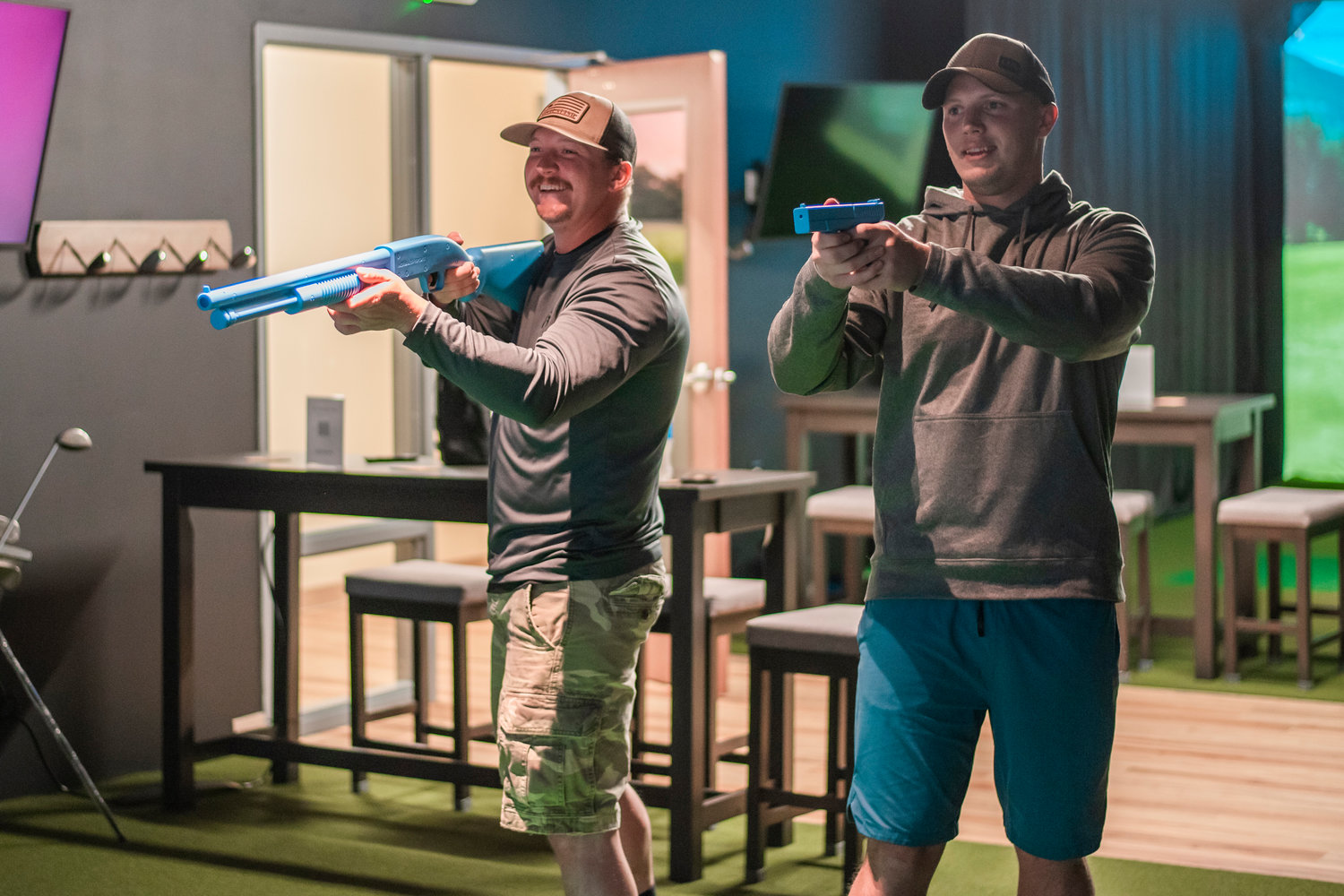 Visitors smile while using controllers shaped like weapons to fight monsters, aliens and zombies in various games at Par 4 Sports in Centralia.