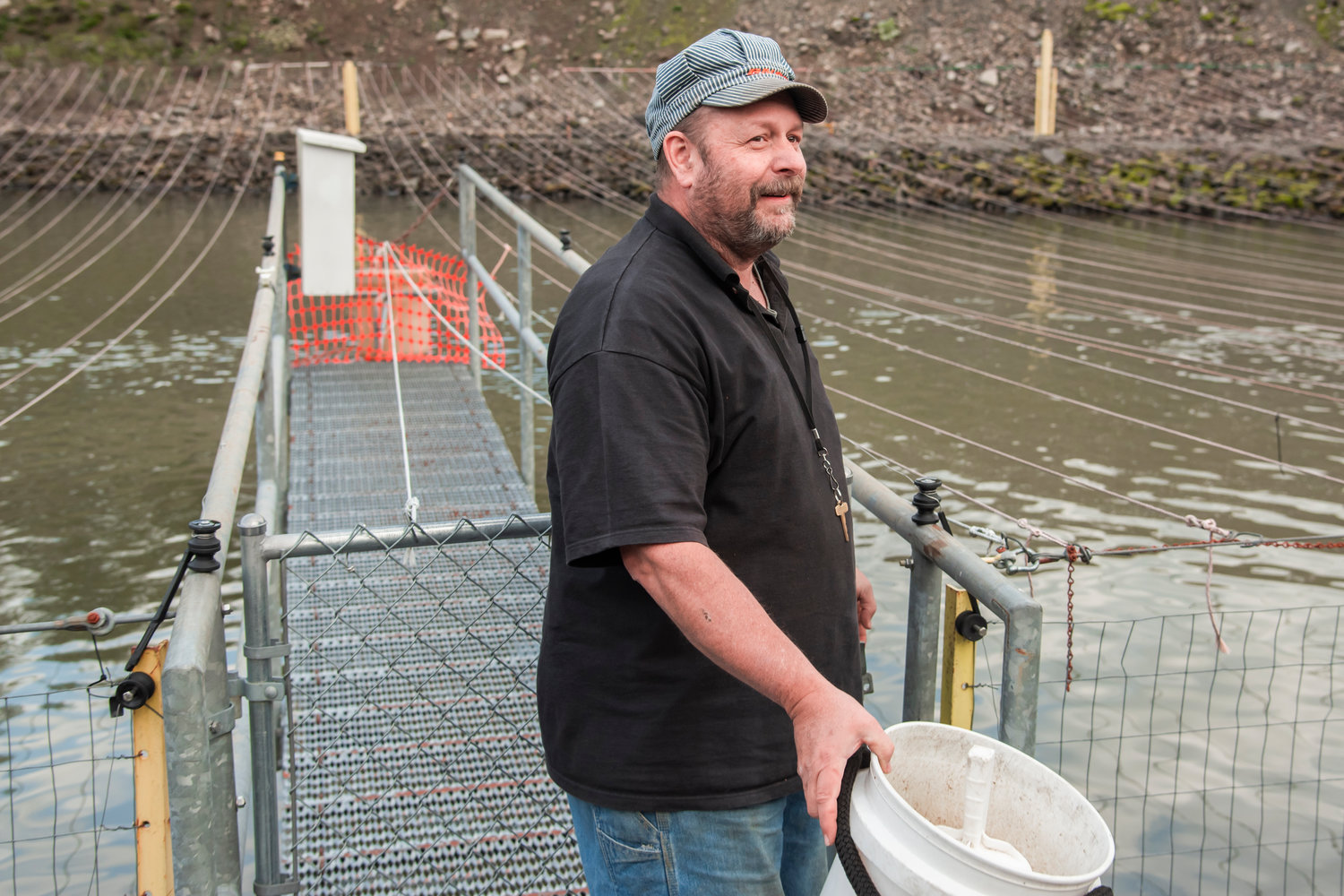 Alan Boerner, a hydro operator with TransAlta, smiles while feeding salmon in a rearing pond at the Skookumchuck Dam Wednesday in Thurston County.