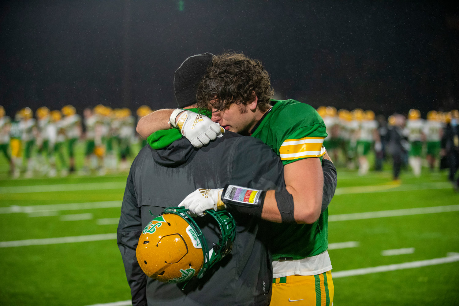 Tumwater senior Ryan Otton hugs a Thunderbirds’ assistant coach after the T-Birds lost 21-7 to Lynden in the 2A state football championship on Dec. 4 in Puyallup.