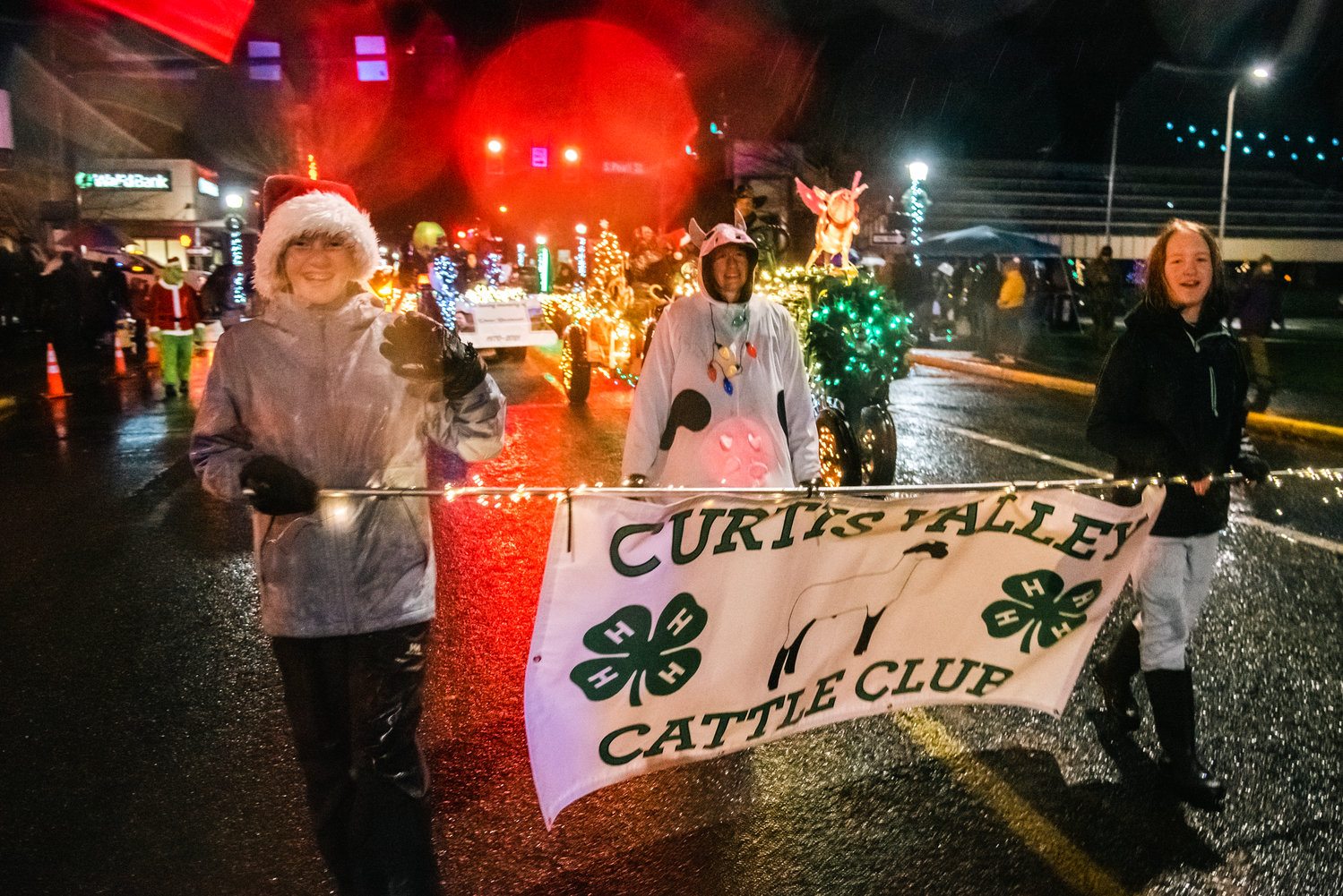 Members of the Curtis Valley Cattle Club smile and wave during the Lighted Tractor Parade in Centralia Saturday night.