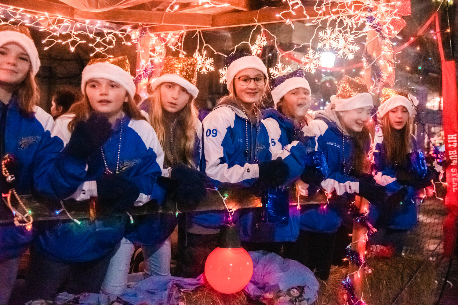 Members of Sabotage Northwest smile and wave from a float during the Lighted Tractor Parade in Centralia Saturday night.