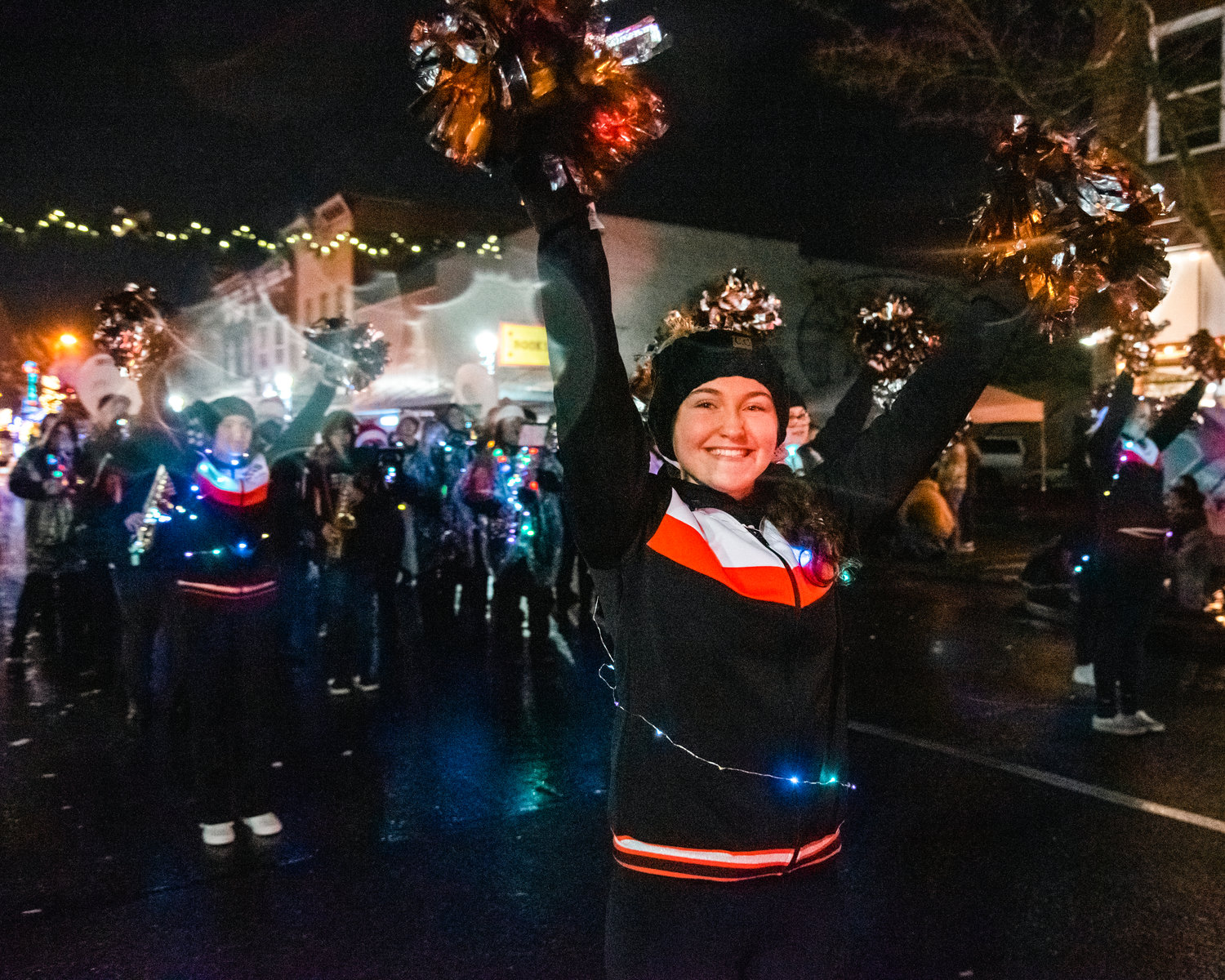 Members of Centralia Tiger Marching Band and Cheer Squad smile and wave as music plays during the Lighted Tractor Parade in Centralia Saturday night.