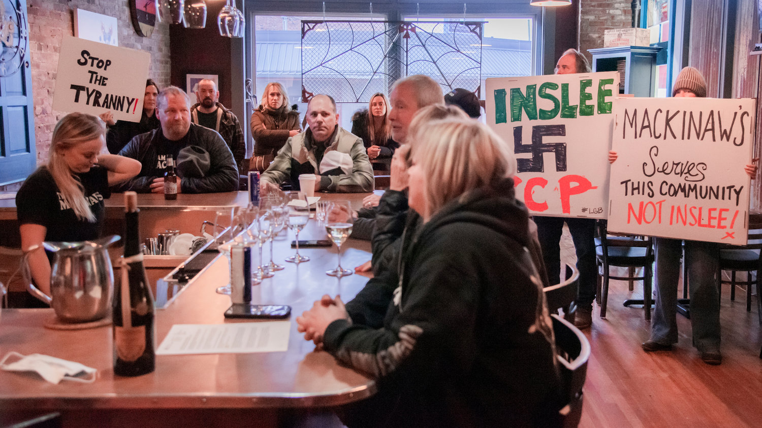 Supporters hold signs and mingle Friday morning at Curious The Bar in Chehalis.