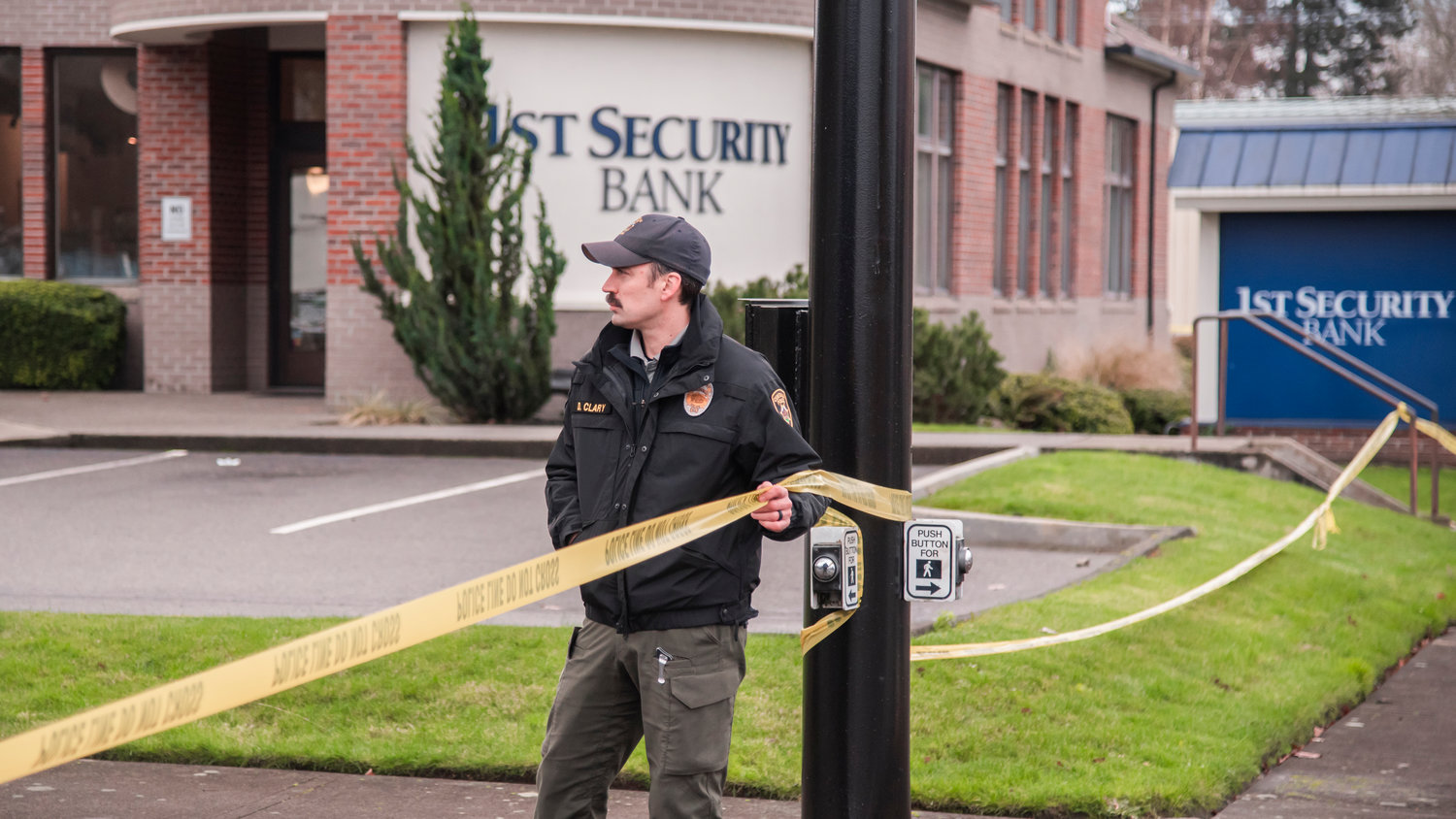 Detective Sgt. Dave Clary holds police line tape wrapped around 1st Security Bank in Centralia Sunday morning.