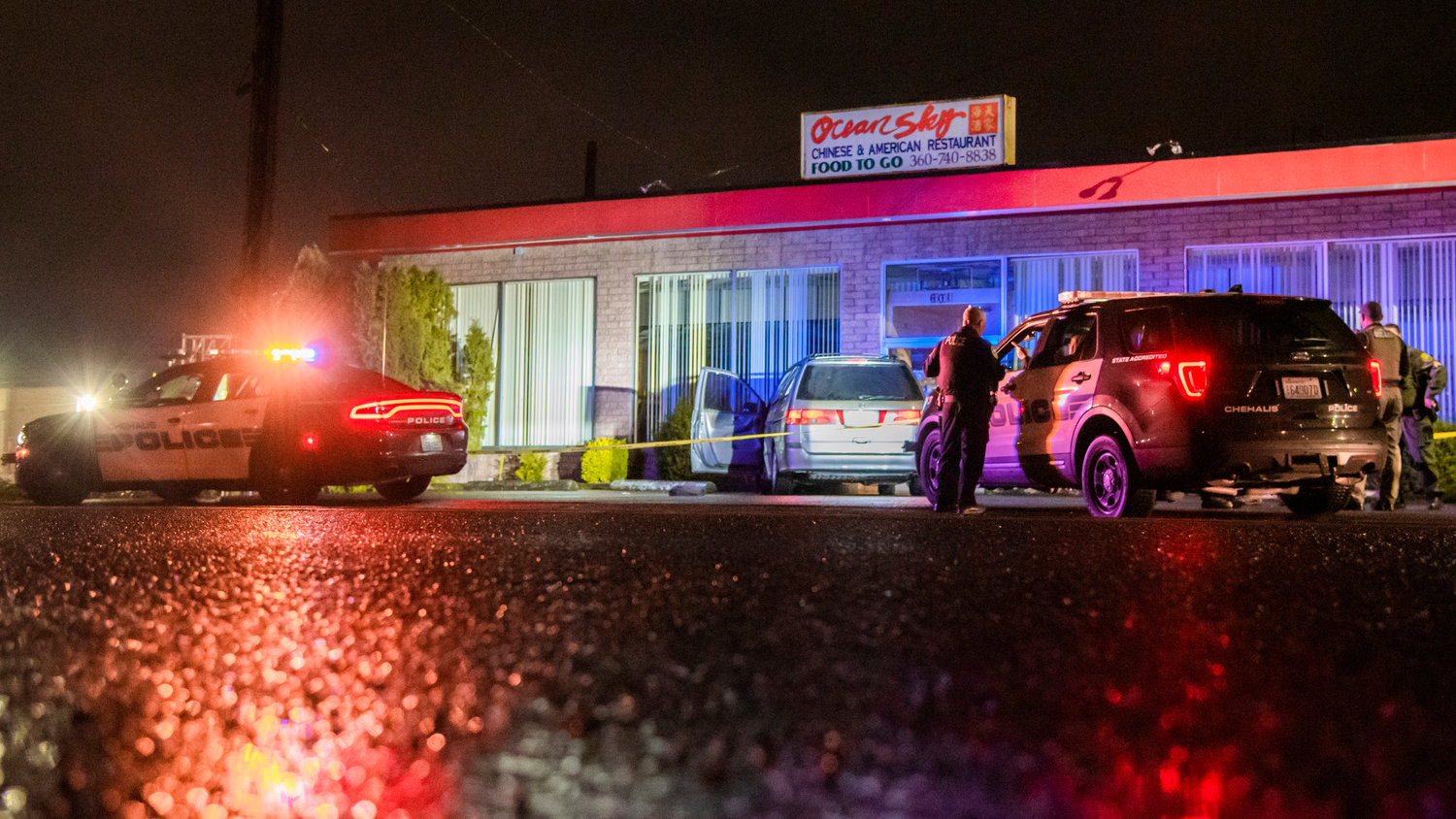 Chehalis Police surround a vehicle outside the Ocean Sky Chinese & American Restaurant Monday night as police tape stretches around the building.