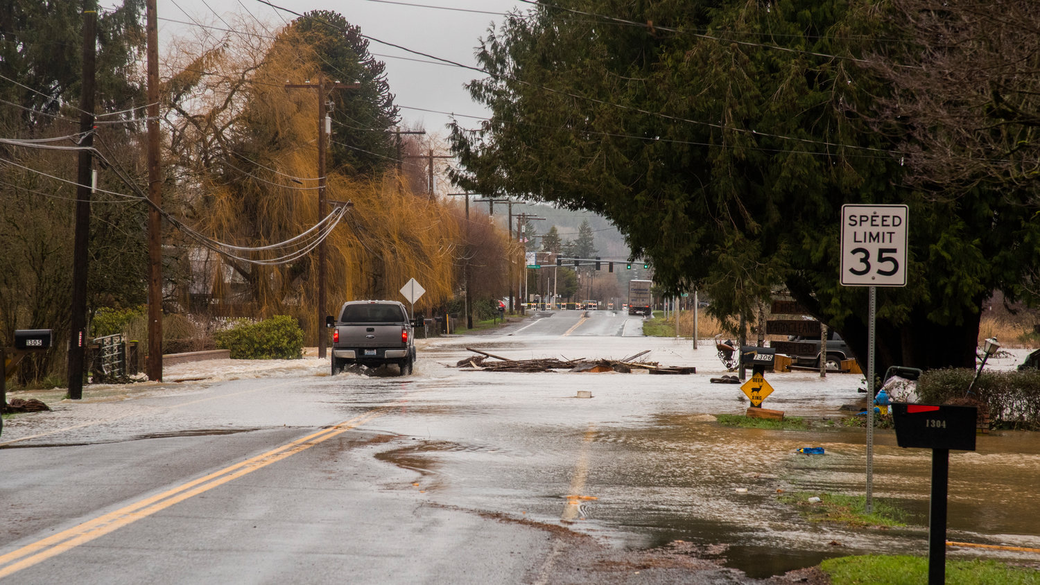 A truck drives by debris in the Skookumchuck River Friday in Centralia as floodwaters flow over North Pearl Street.