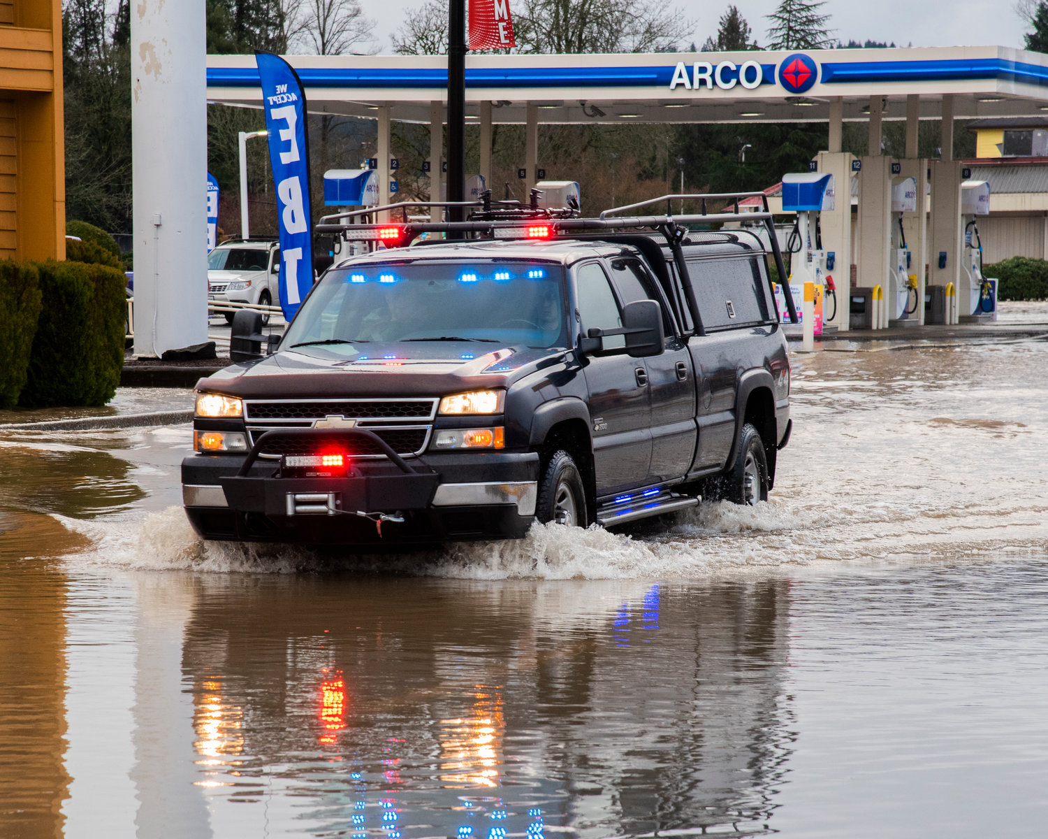 Law enforcement vehicles drive through floodwaters along Harrison Avenue in Centralia on Friday.